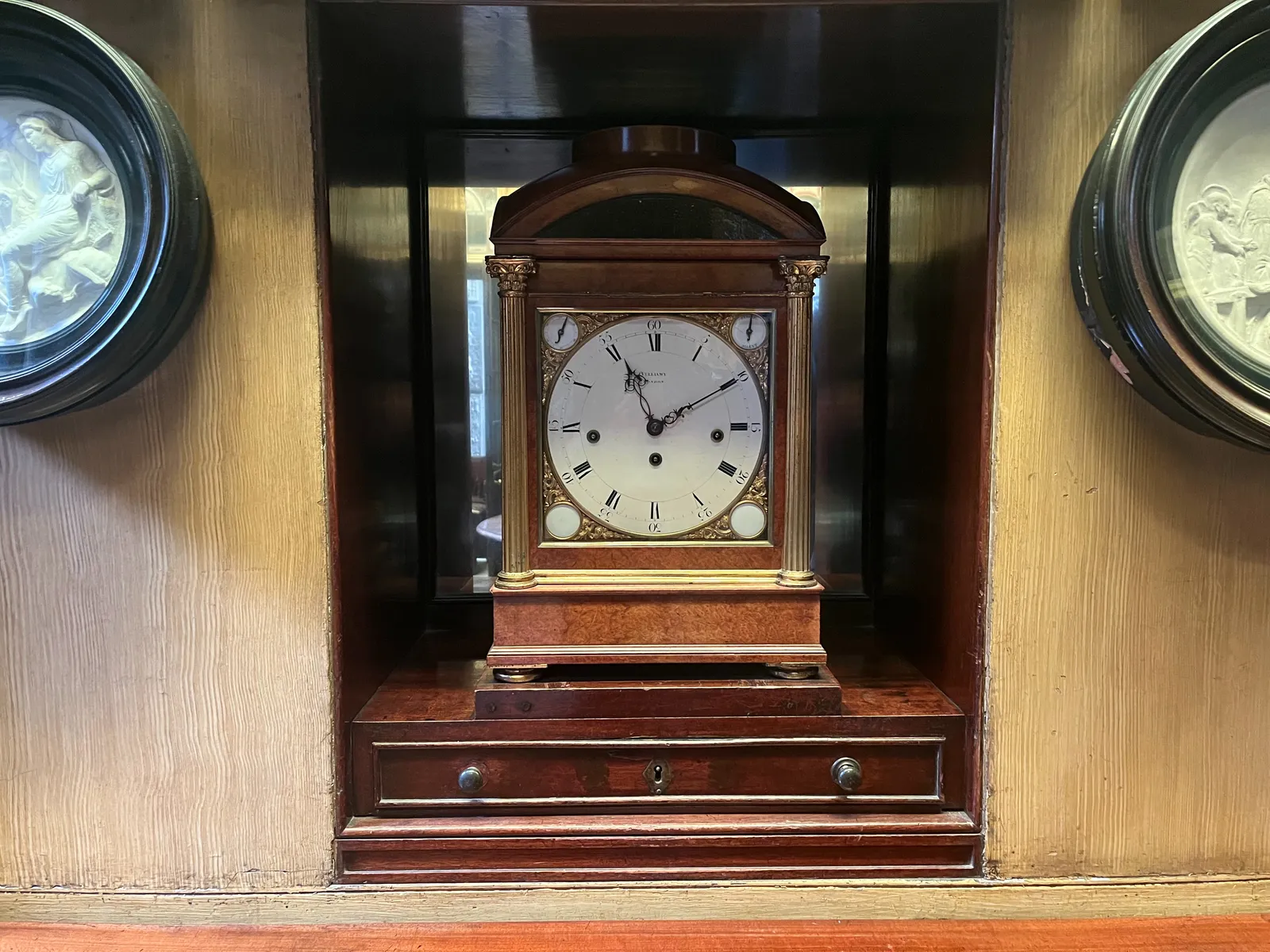 A very old wooden clock that points at 10 past 11.