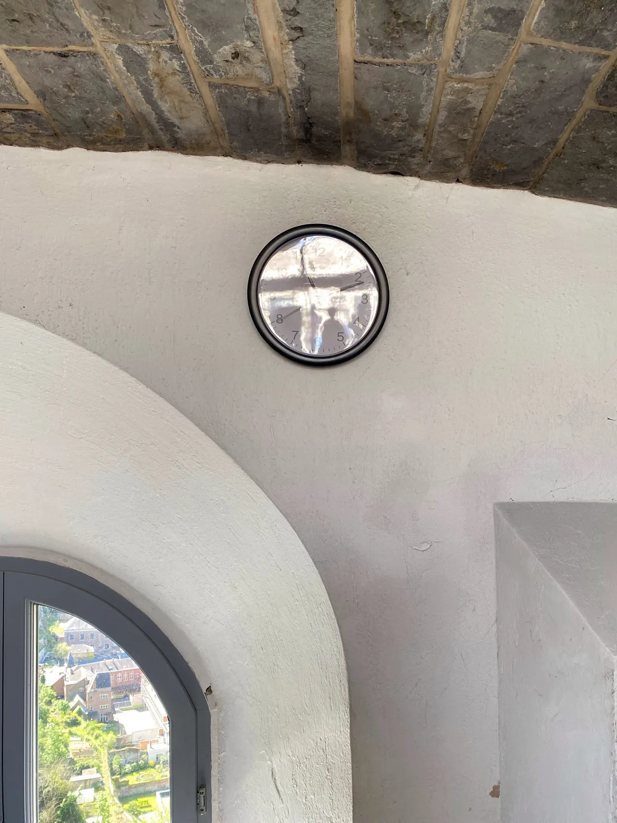 There’s a small window through which you can look down upon some houses. Next to this window on the wall there’s a clock. It’s hard to see the time because of some bright reflection on the cover. But with a bit of trouble you can see that the clock points at 11 minutes past 11.