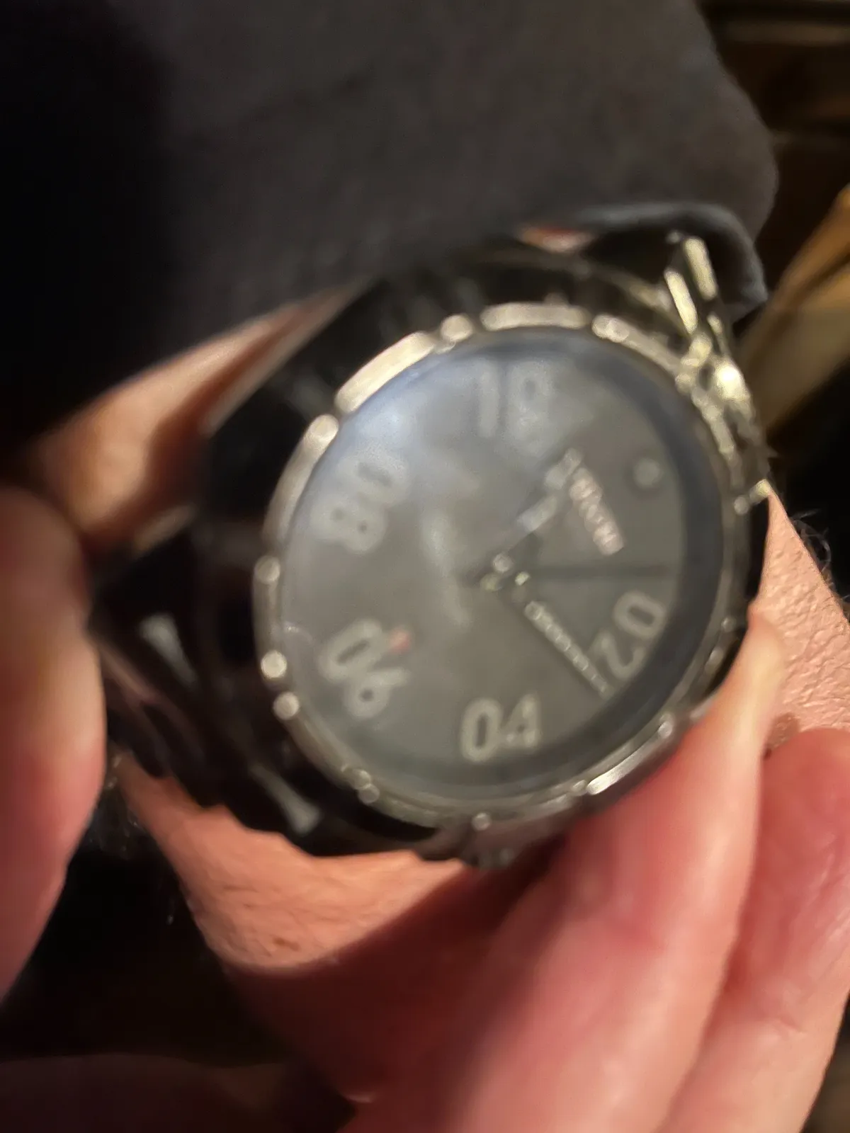 A blurry picture of a wrist watch. Even though it’s blurry you can see that only the even numbers are shown. It seems to points at approximately 13 past 11.