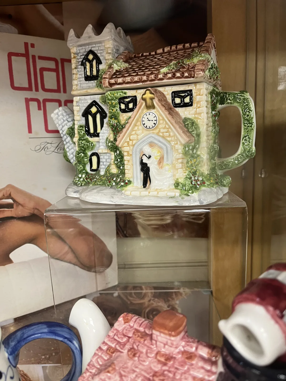 A ceramic castle for sale in a thrift shop, with a couple getting married entering. There’s a clock painted on this thing, which points at a quarter past eleven.