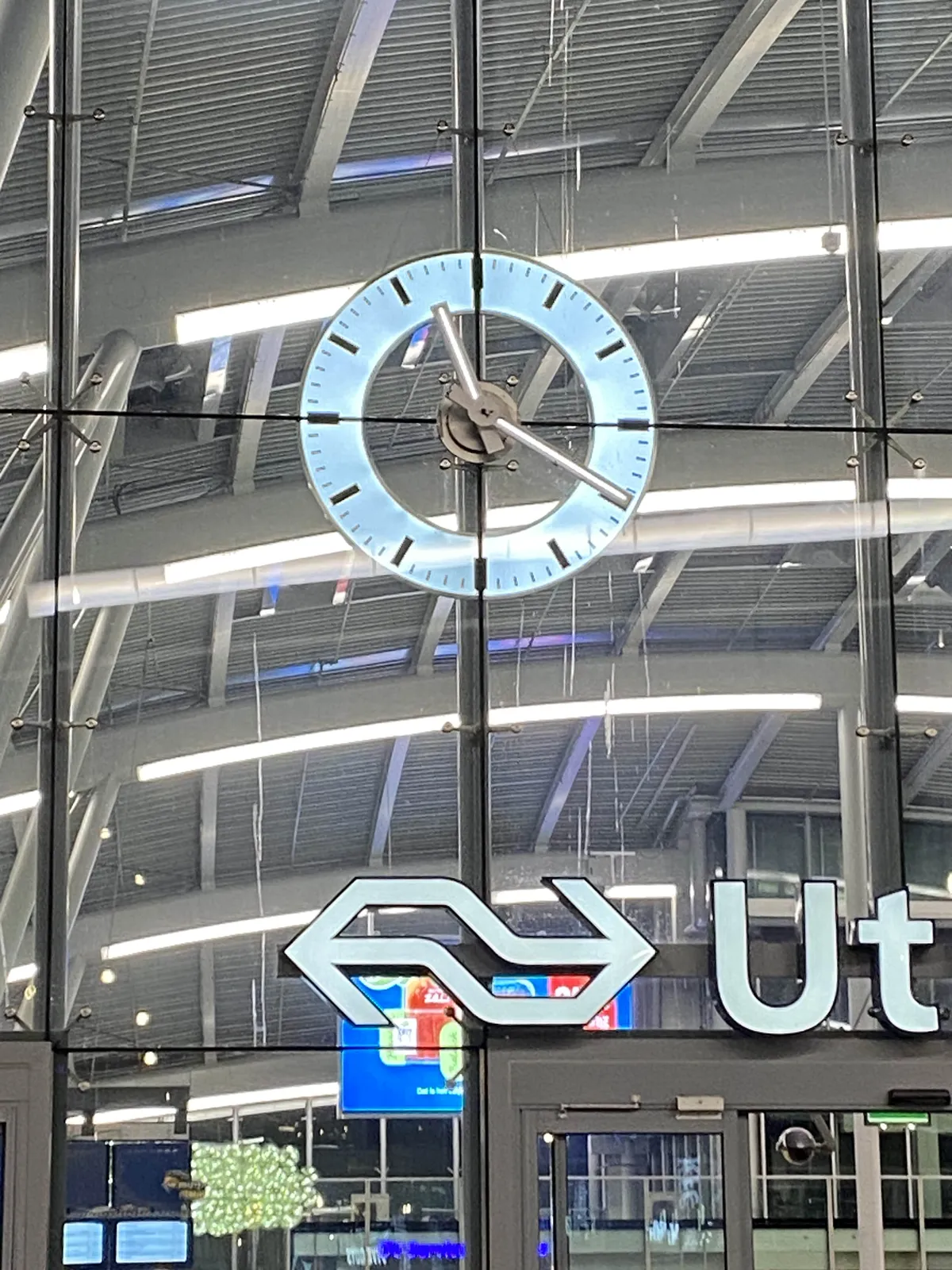 A large clock on the large glass facade of a large train station. It points at 20 past 11.