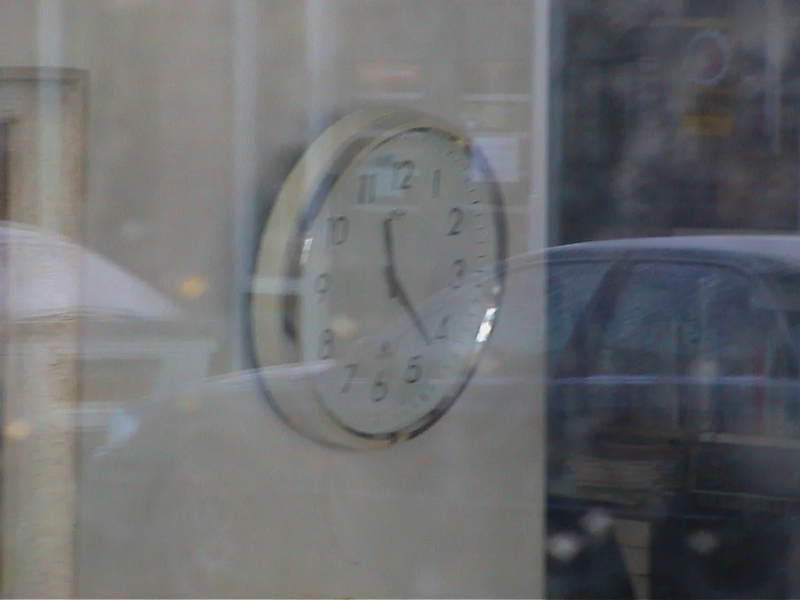 On this clock, seen through a window, it is 22 past 11.