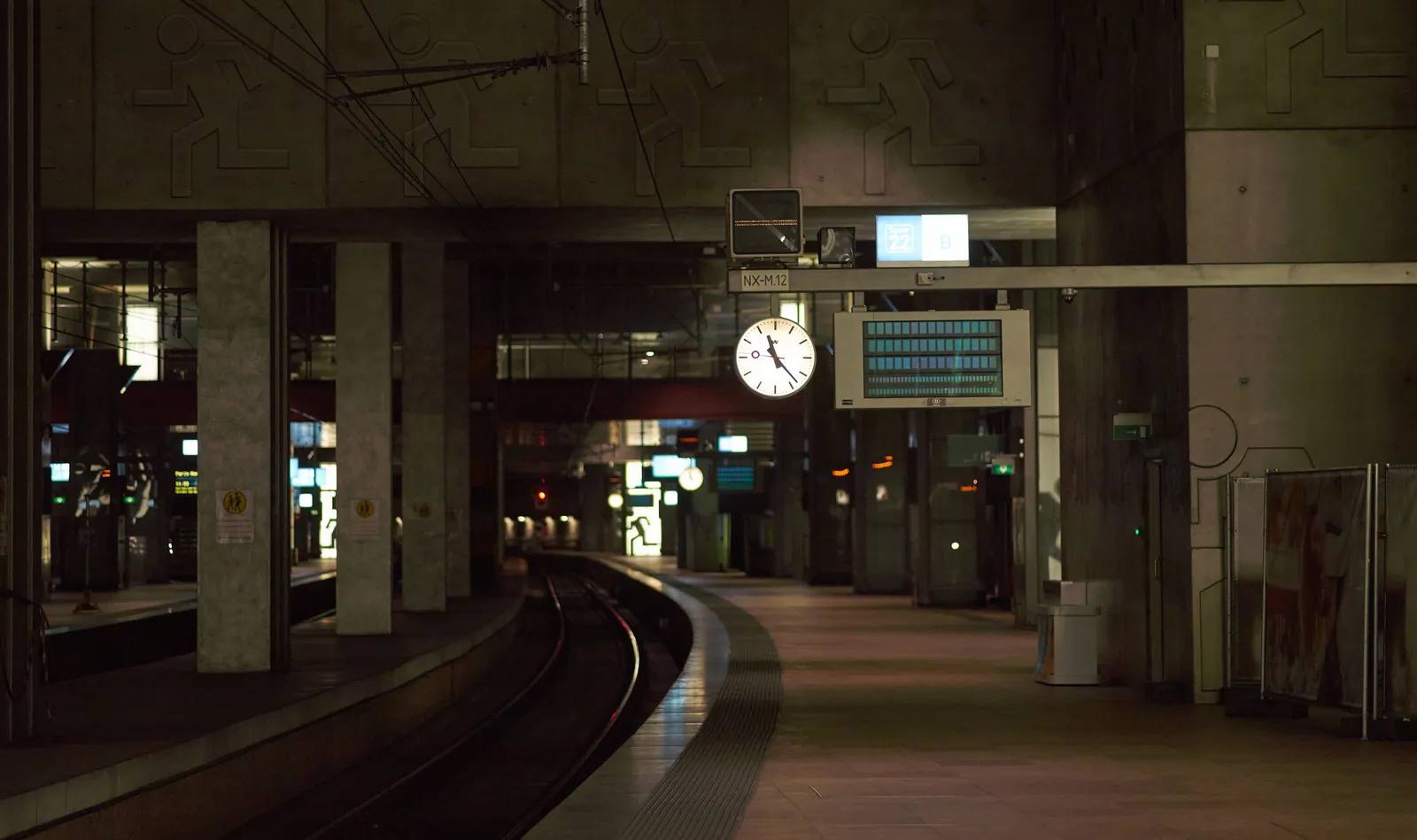 A dark tunnel at Antwerp Train station. The clock in the middle of the image points at 23 past 11.