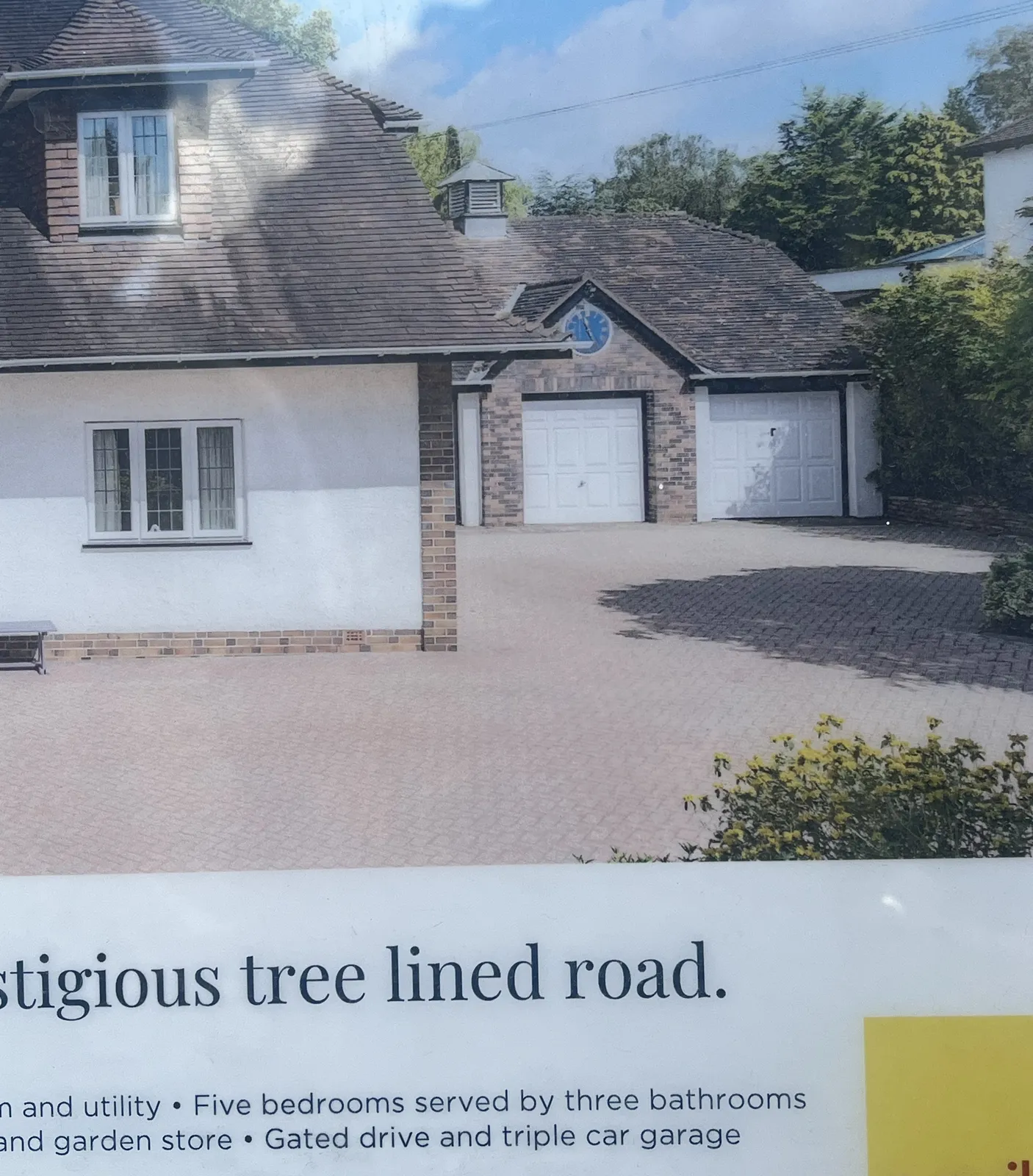 A picture of an advertisement for a villa that is for sale. There’s a clock on the garage of this villa that points at 25 minutes past eleven.