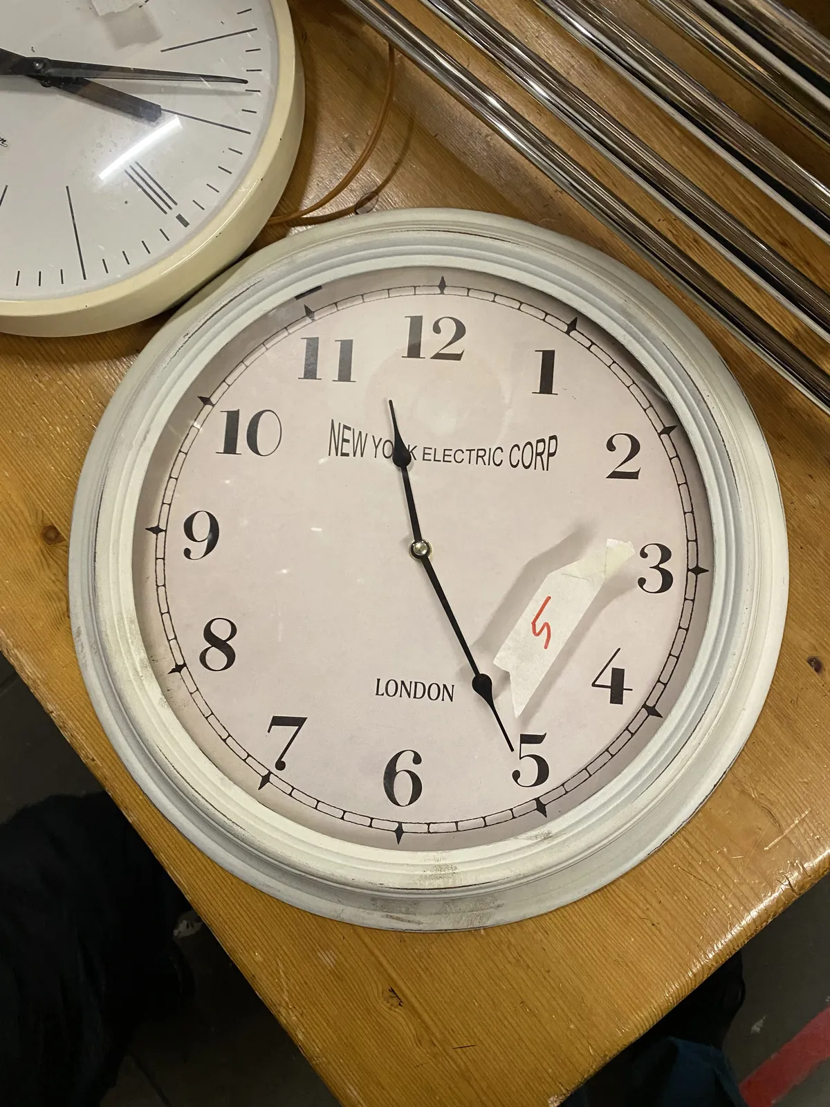 A clock laying on a table points at 25 past 11.