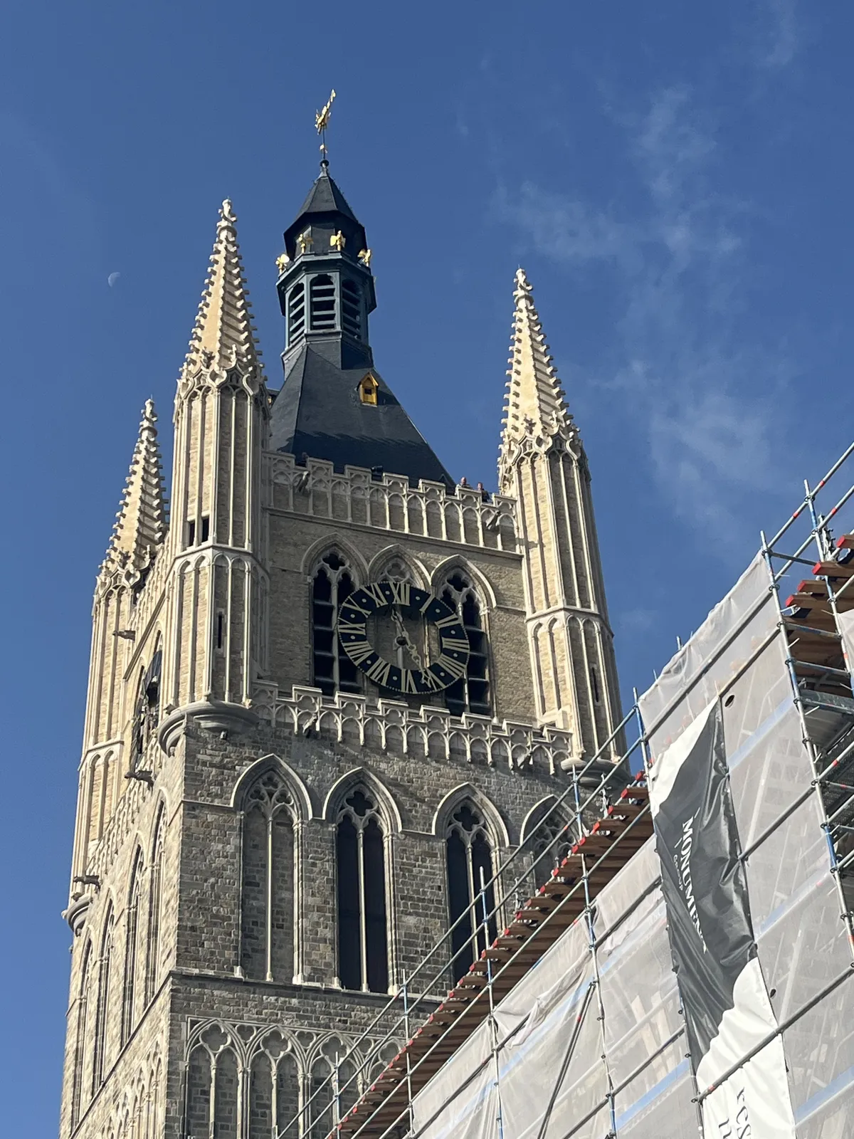Part of this church is wrapped in plastic and scaffolding, but not the tower with the clock on it. The clock points at approximately 26 minutes past 11.