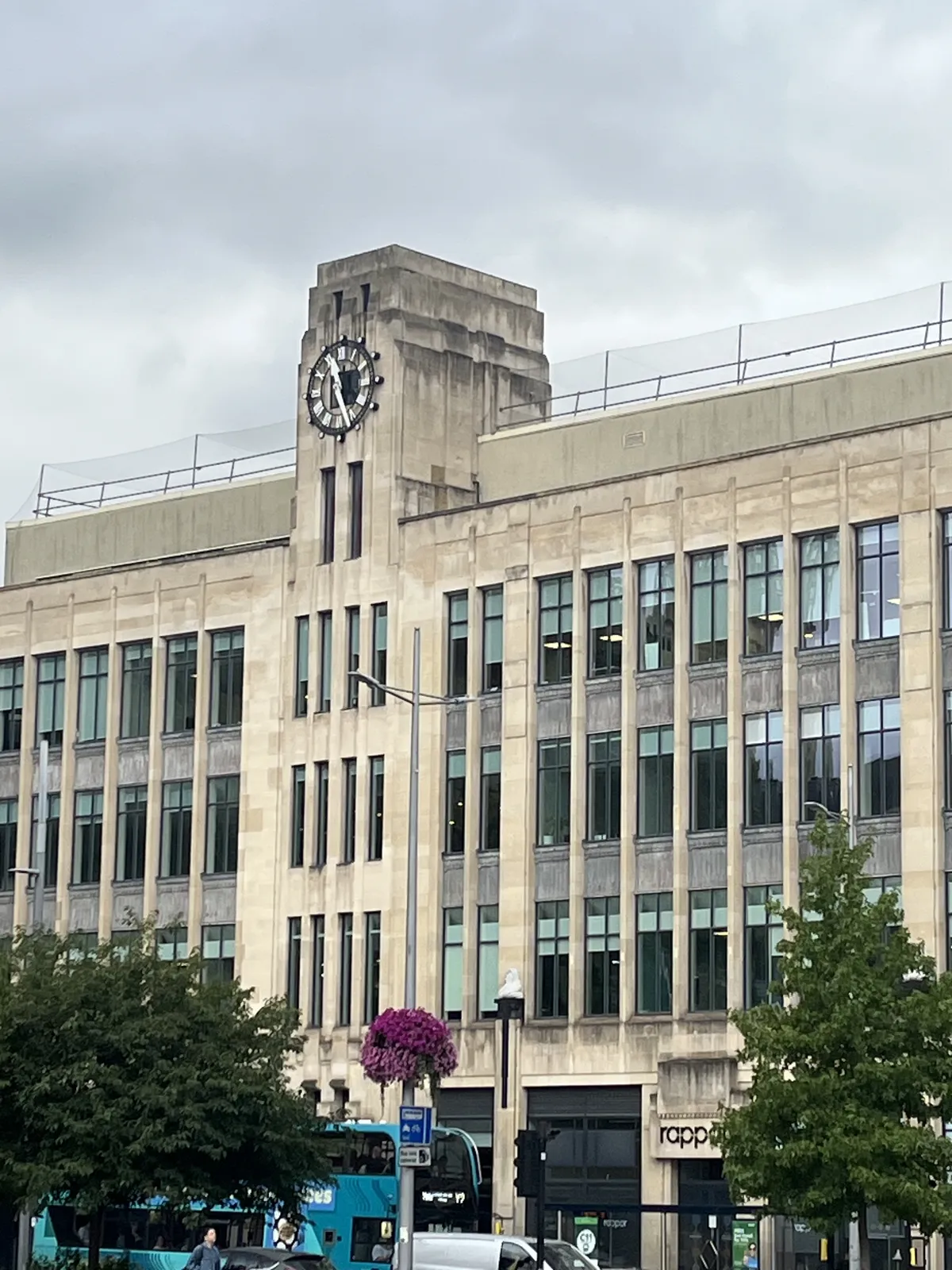 A clock on top of a modernist, almost brutalist concrete building points at 27 minutes past eleven.