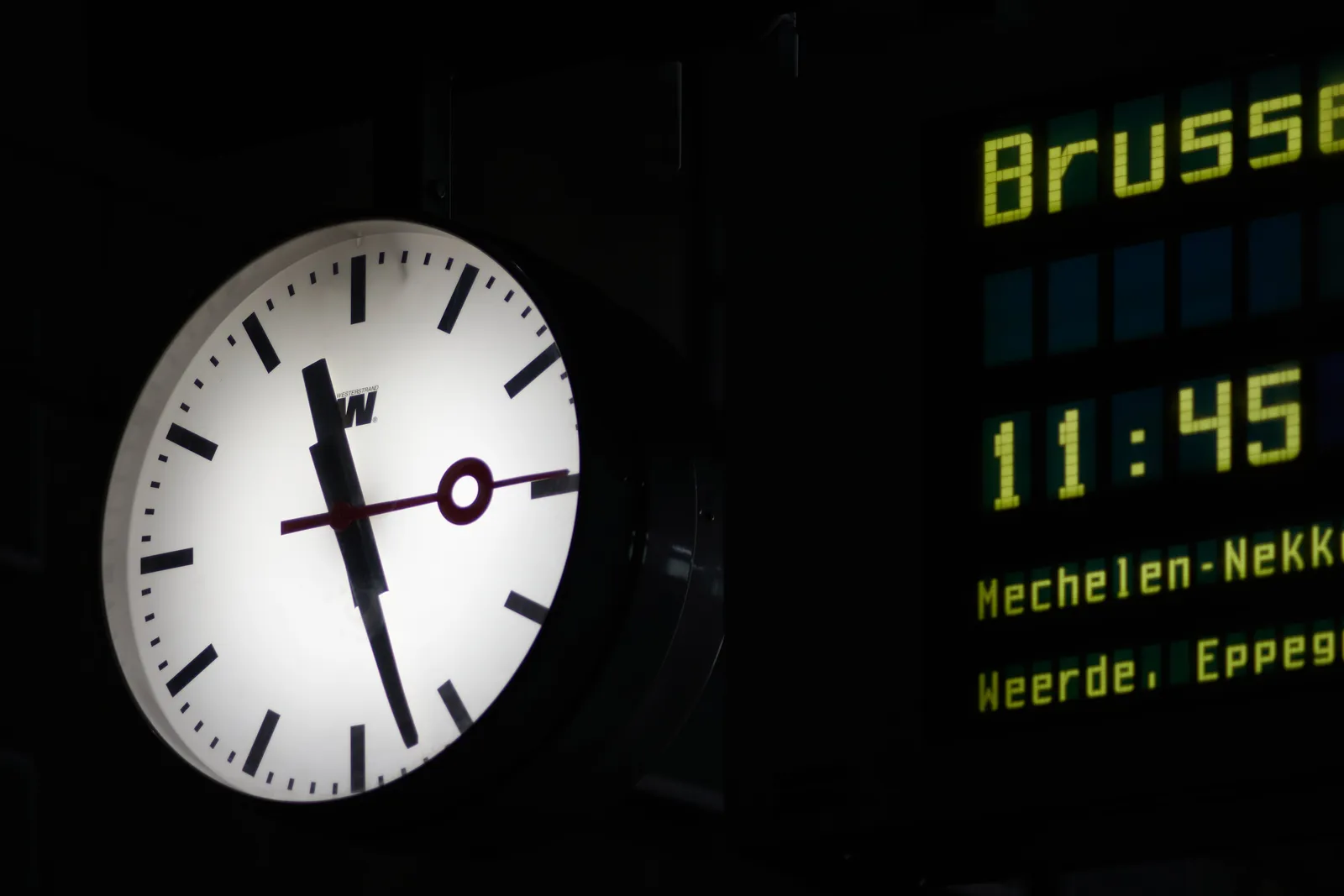 A clock on a station points at 27 past 11.