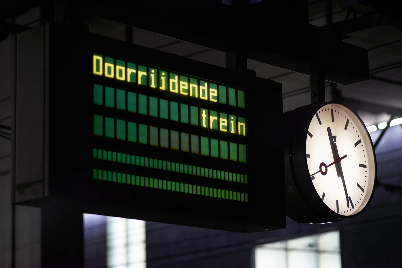 The sign warns for a passing train. According to the clock next to it it points at 27 past 11.