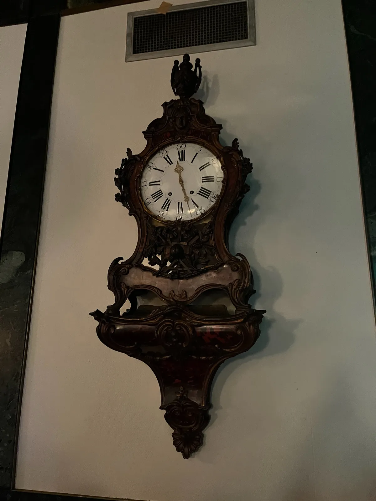 An old wooden wall clock. It points at 27 minutes past 11.