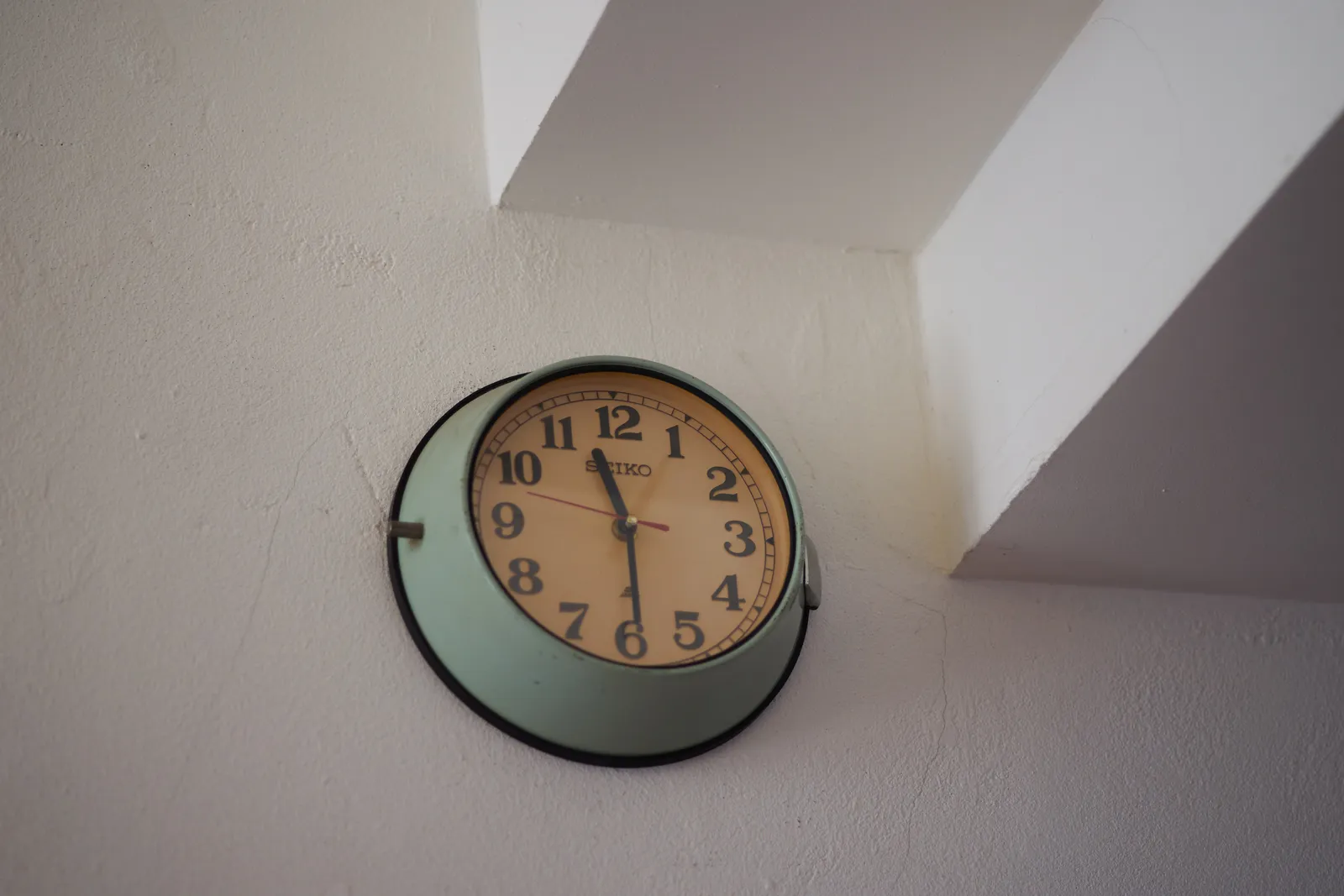A wall clock in a minty blue/green colour points at 29 past 11.