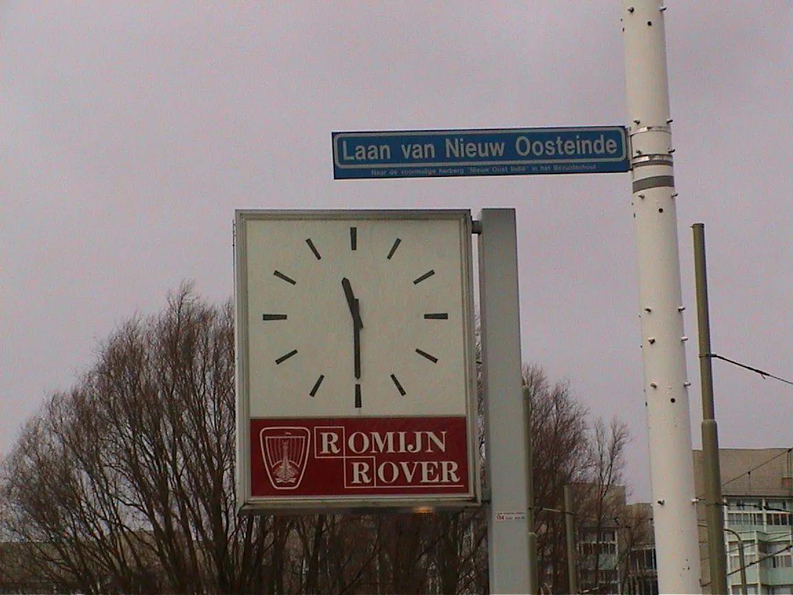 This clock, attached to a pole, points at half past 11.