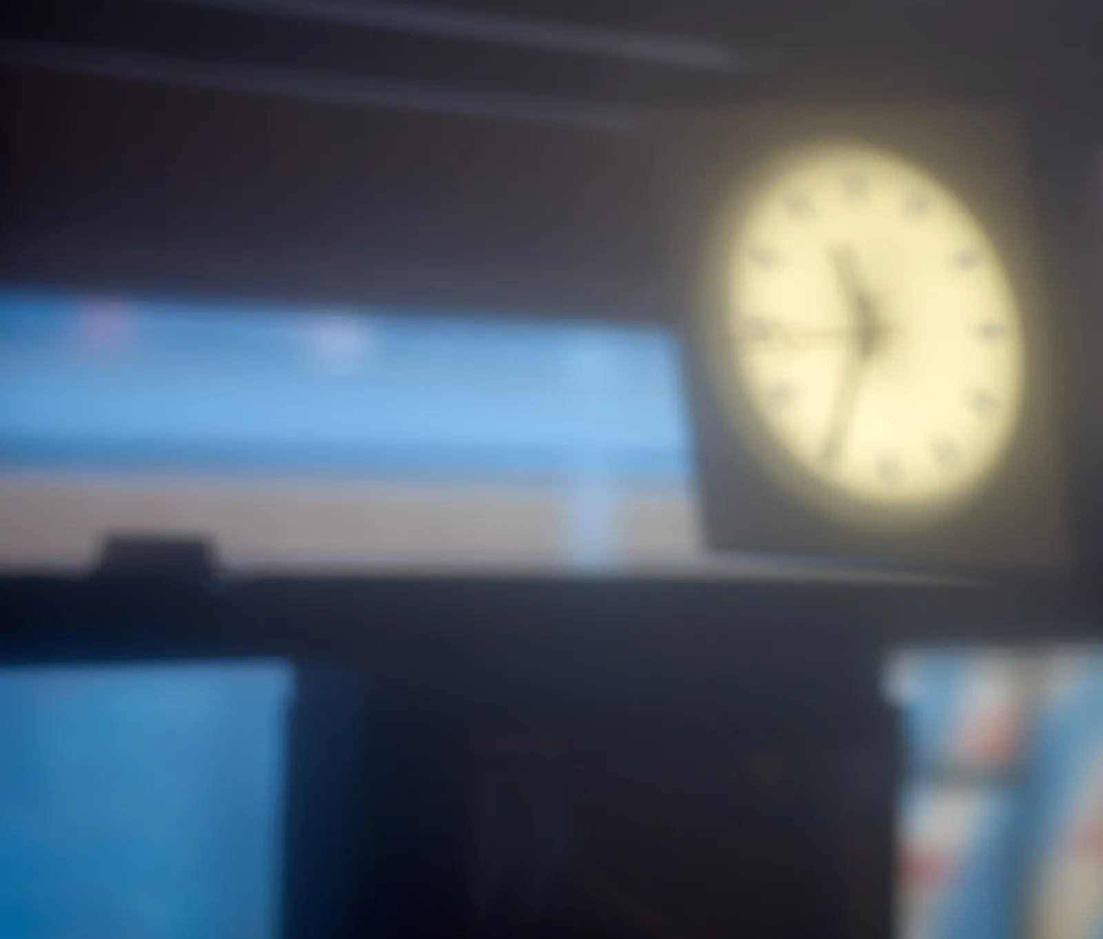 A blurry picture of a clock that seems to point at 34 past 11.