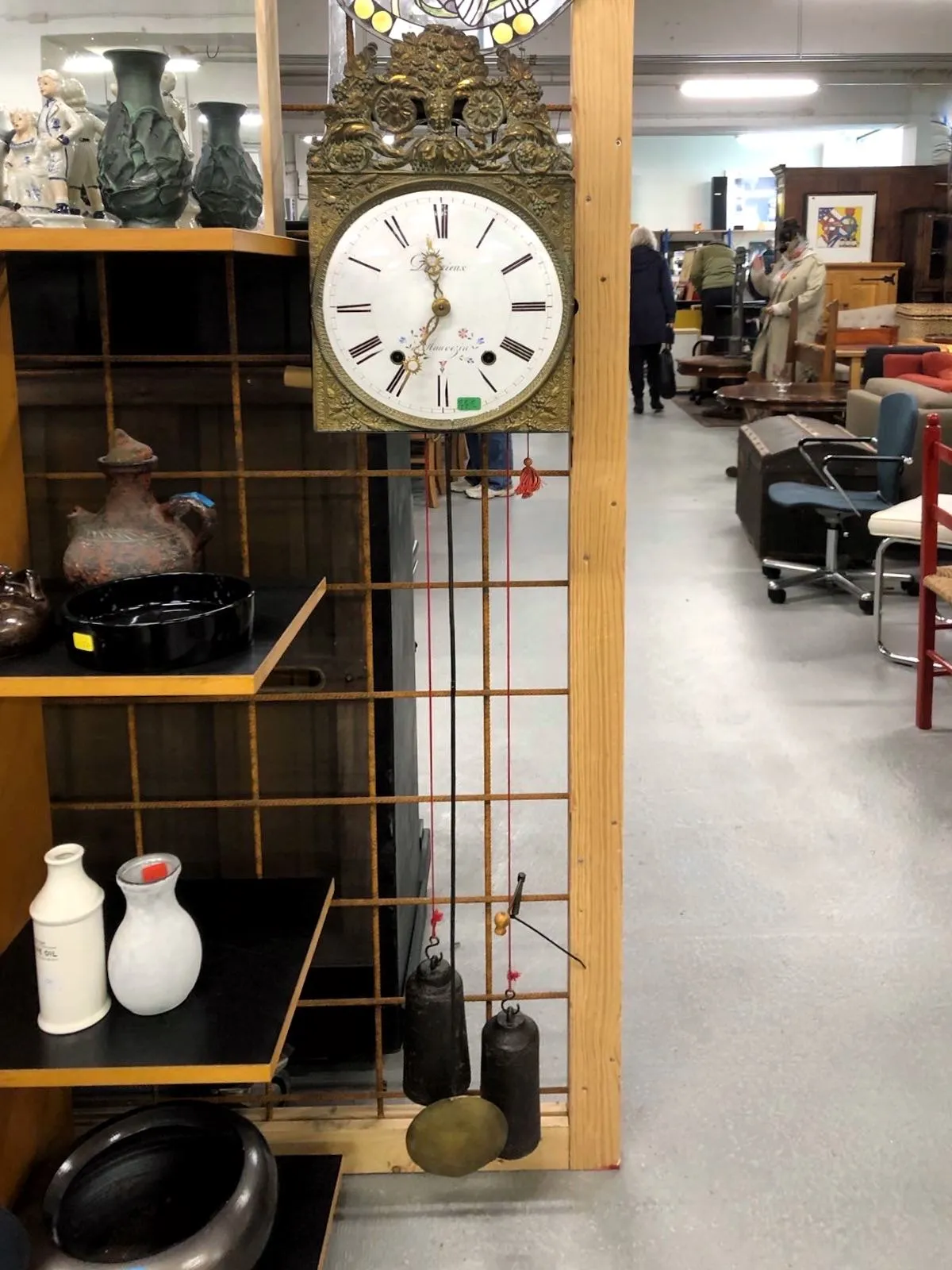 An old clock with weights and a pendulum. It points at 34 past 11.
