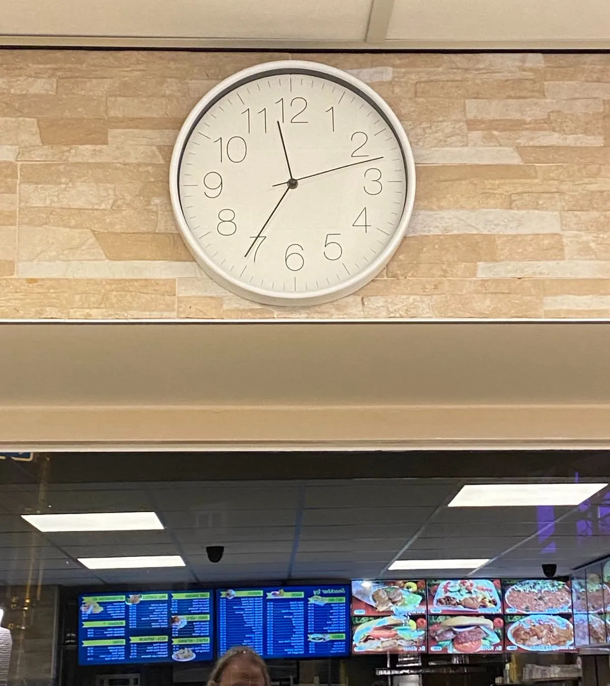 A clock in a snack bar. It points at 36 minutes past 11.