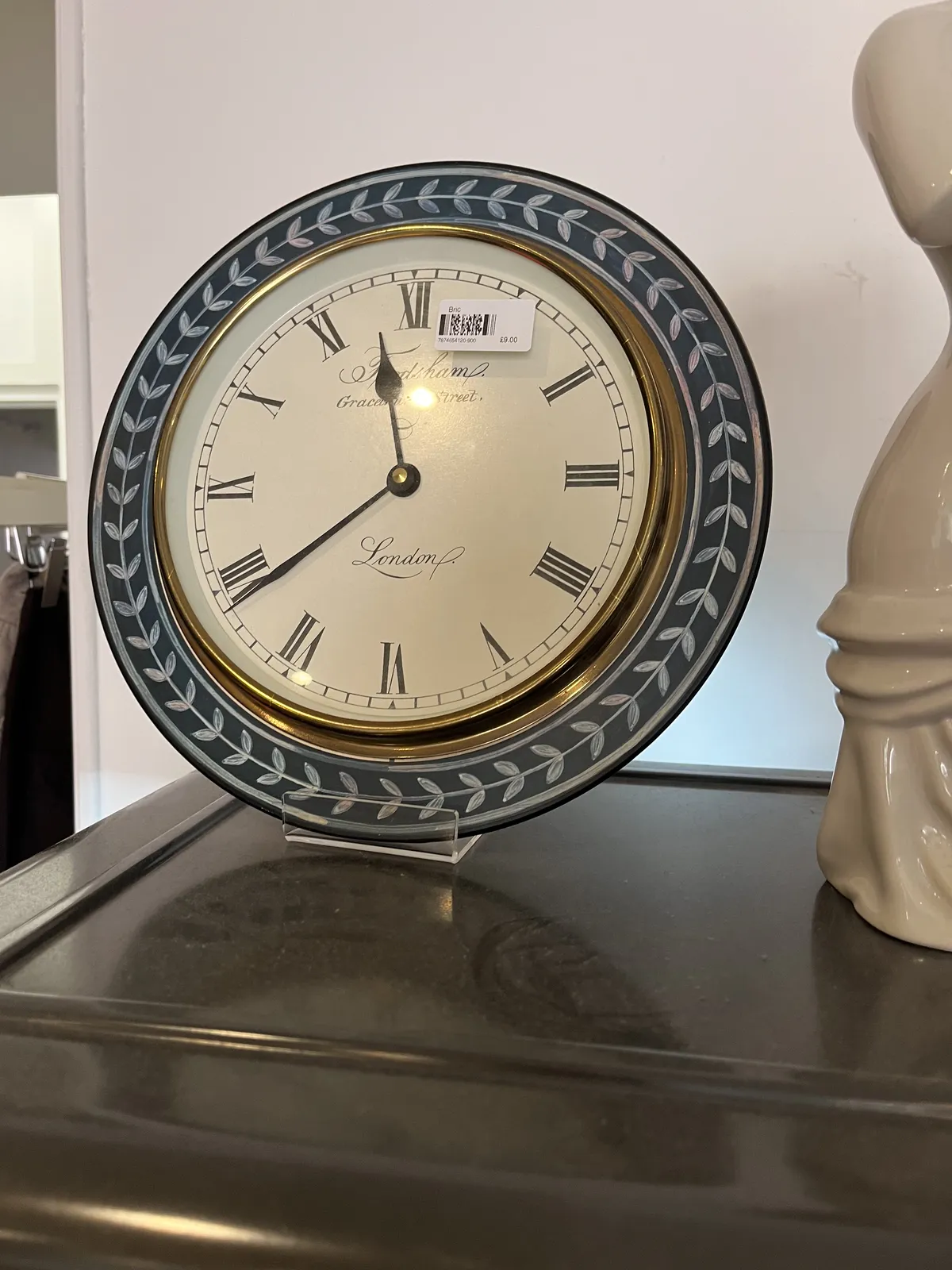 An antique looking wall clock for sale. It points at 21 minutes to twelve.