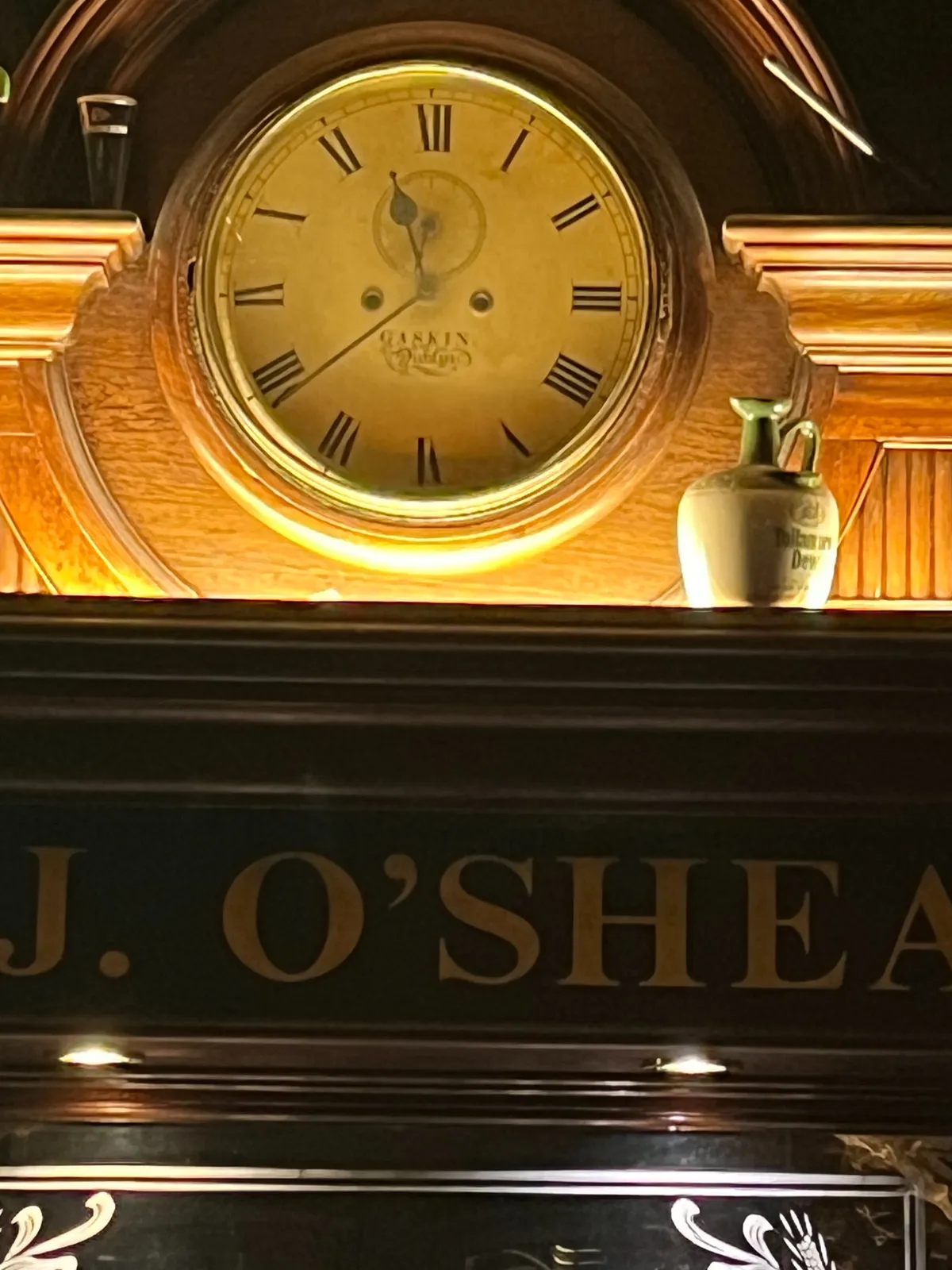 A old wooden clock in an Irish pub. It points at 21 minutes to 12.