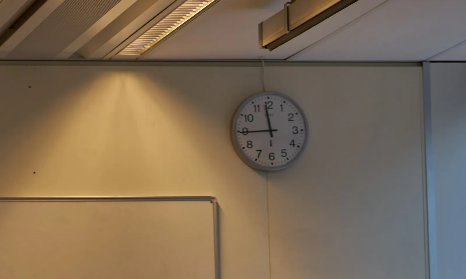 A clock on a wall points it fingers at sixteen minutes to twelve.