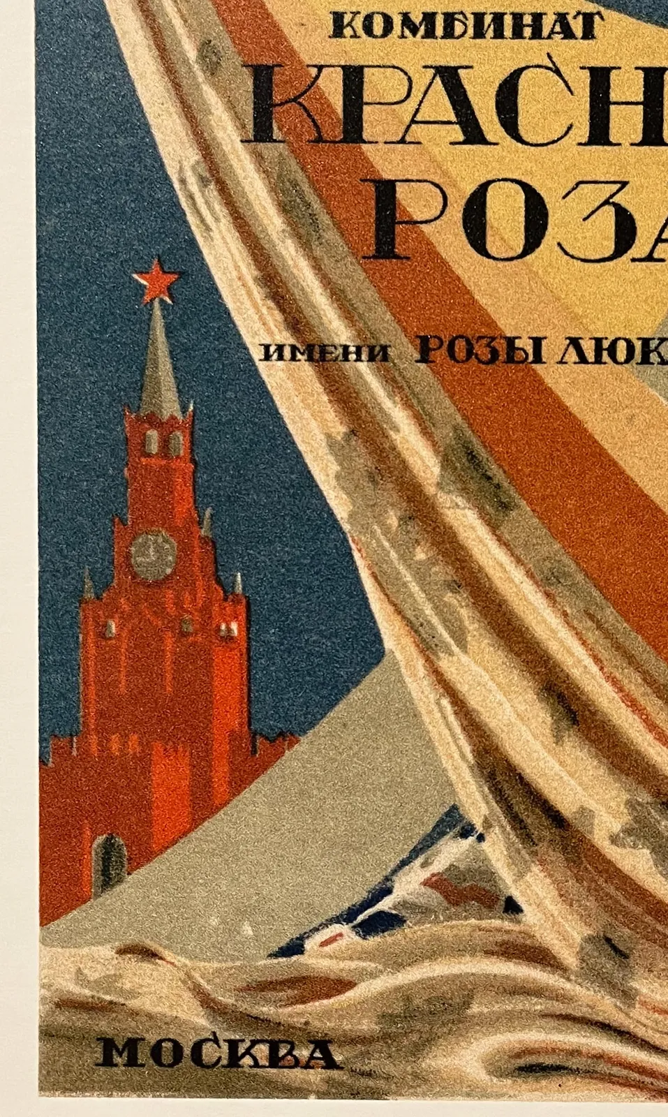 A picture of a detail of an old Soviet poster. In the background there’s a monumental building with a clock on top. It points at a quarter to twelve.