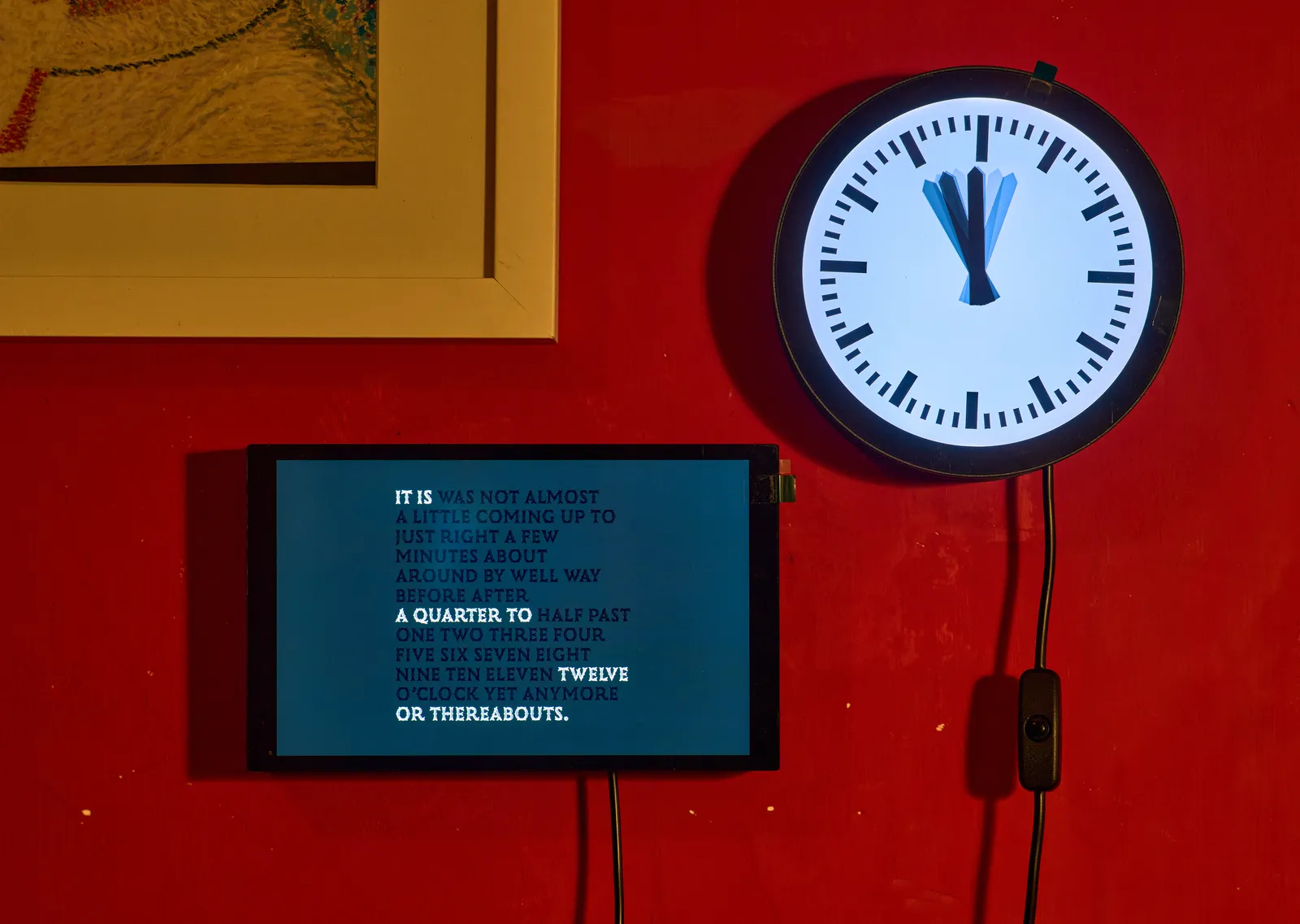 There are two clocks on a red wall. The round one, which is on the right, has at least seven hour hands, that all point to somewhere between eleven and half past twelve. The rectangular one shows all kinds of words on a display that you can use to describe the time without too much precision. A few of these words are highlighted and together they read It is a quarter to twelve, or thereabouts.
