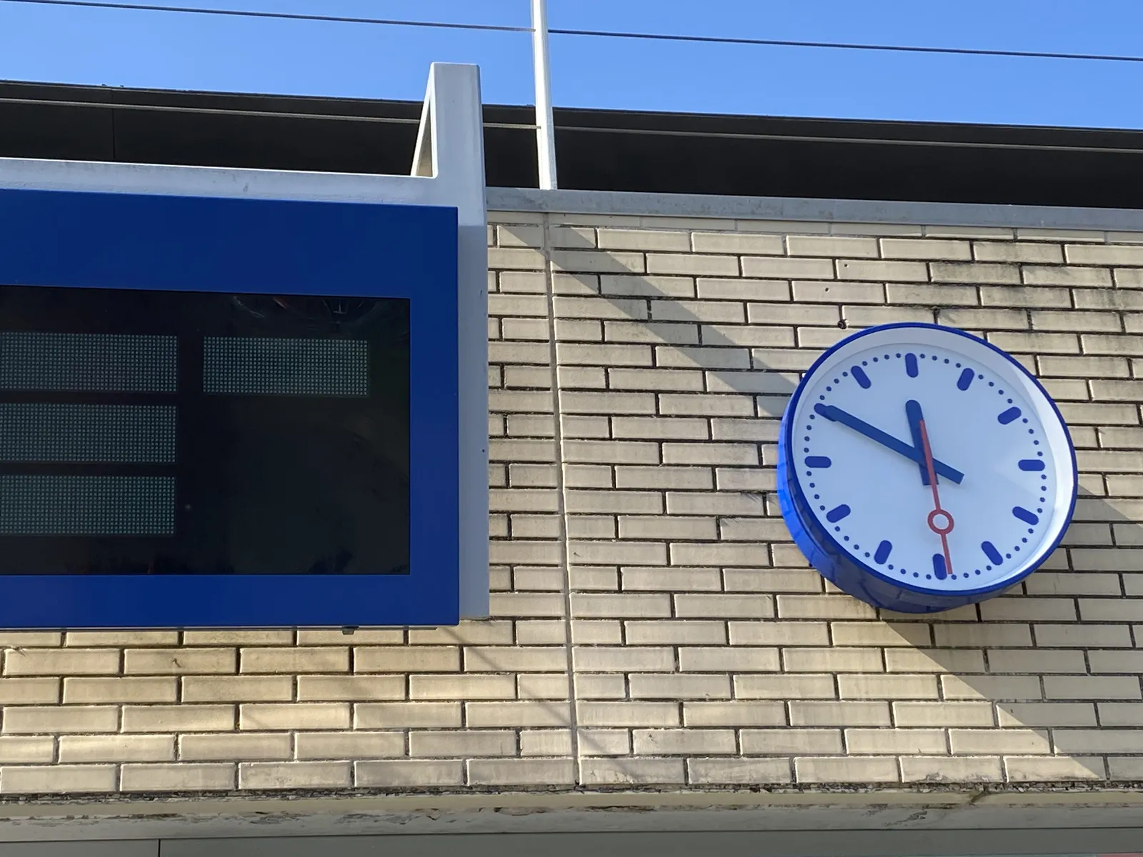 A clock on a train station. It points at 10 to 12.