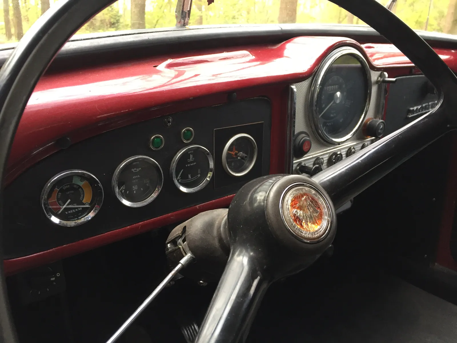 On this dashboard of an old car there are quite some dials. One of them is a clock. On it it is approximately ten to twelve.