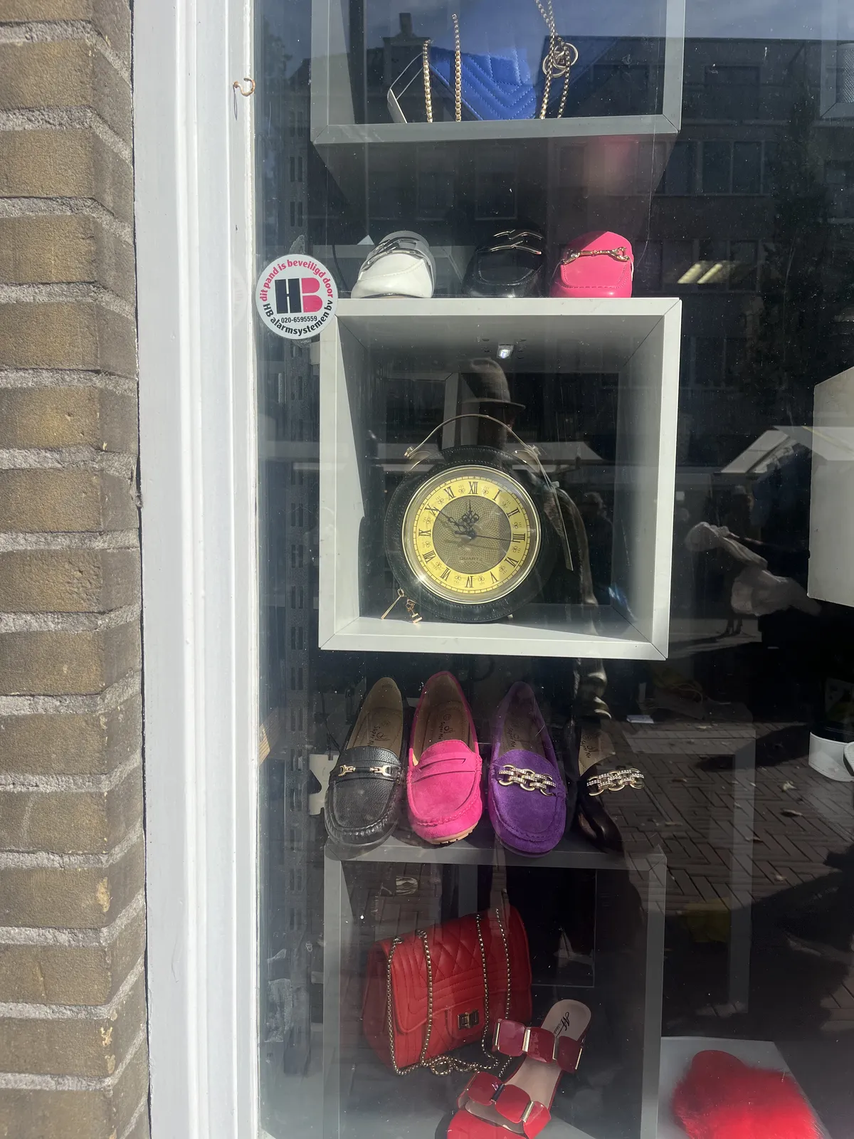 Mostly vintage, colourful shoes for sale in this shopping window. There’s also an old clock, with roman numerals and classic hands, which points at nine minutes to twelve.