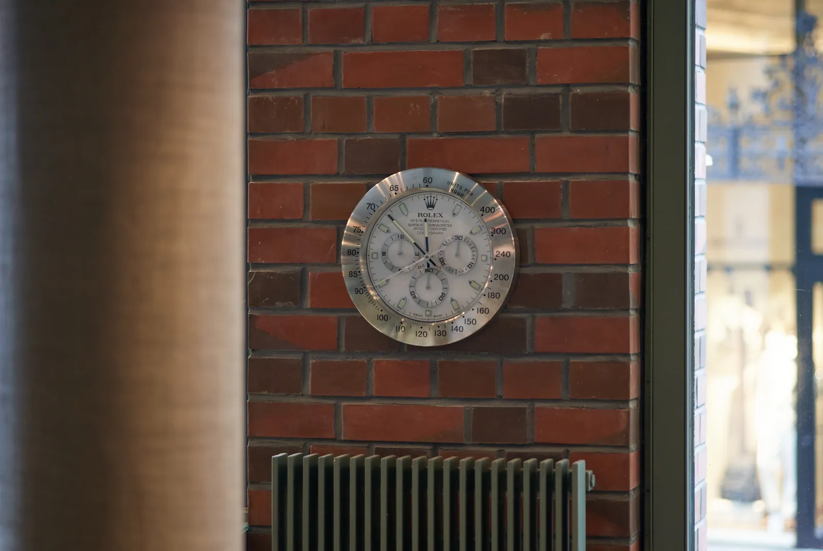 A shiny rolex wall clock points at 8 minutes to 12.
