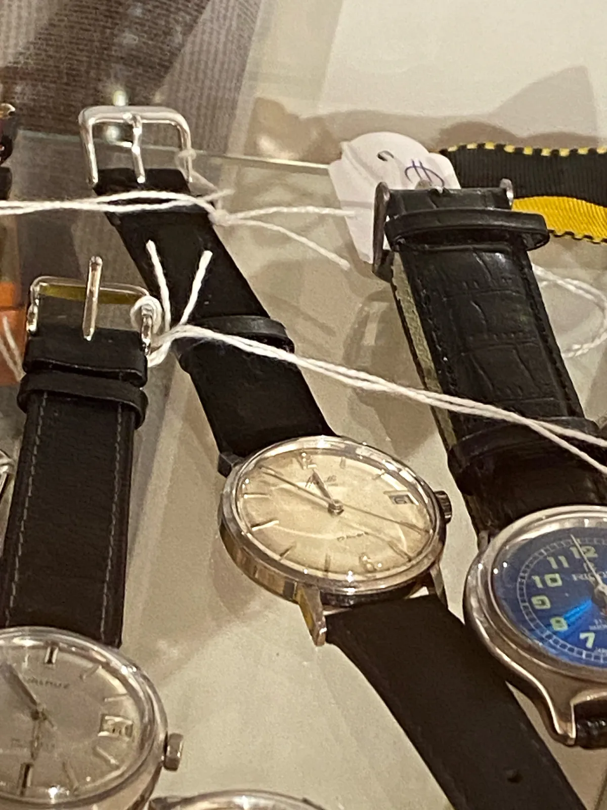 Three watches. The only watch that clearly shows the time points at 6 minutes to 12.