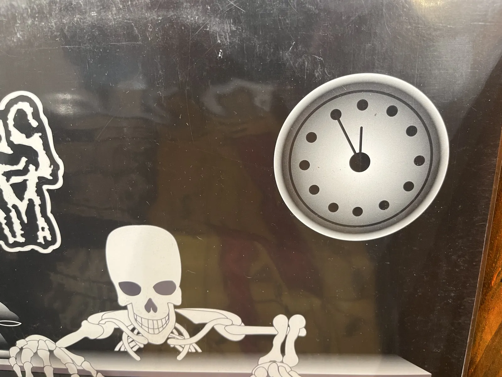 A drawing of a skeleton with a clock above it. The clock points at five minutes to twelve.