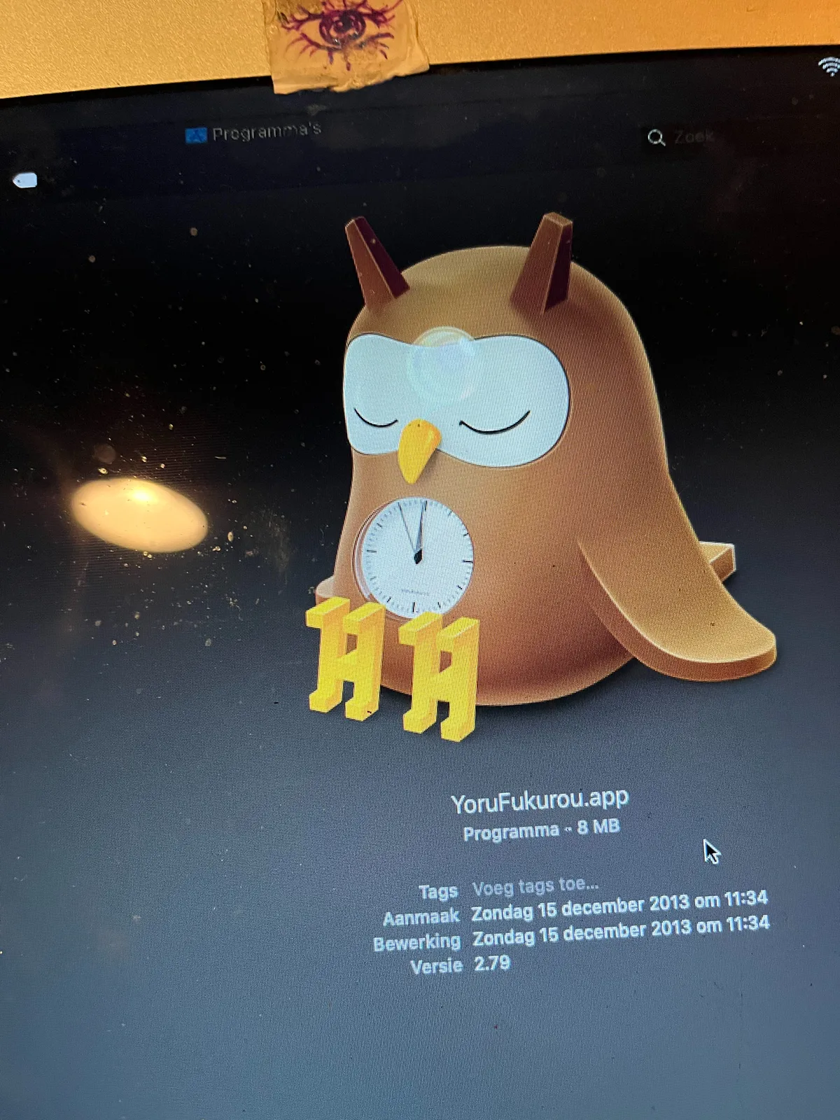 A picture made from a computer screen. On this screen is the picture of a sleeping owl with a clock on its belly. This picture turns out to be the icon of an application called YoruFukurou, which was installed on this computer on Sunday the 13th of December 2013. All this information is on the screen. The clock on the belly of the owl points at five minutes to twelve.