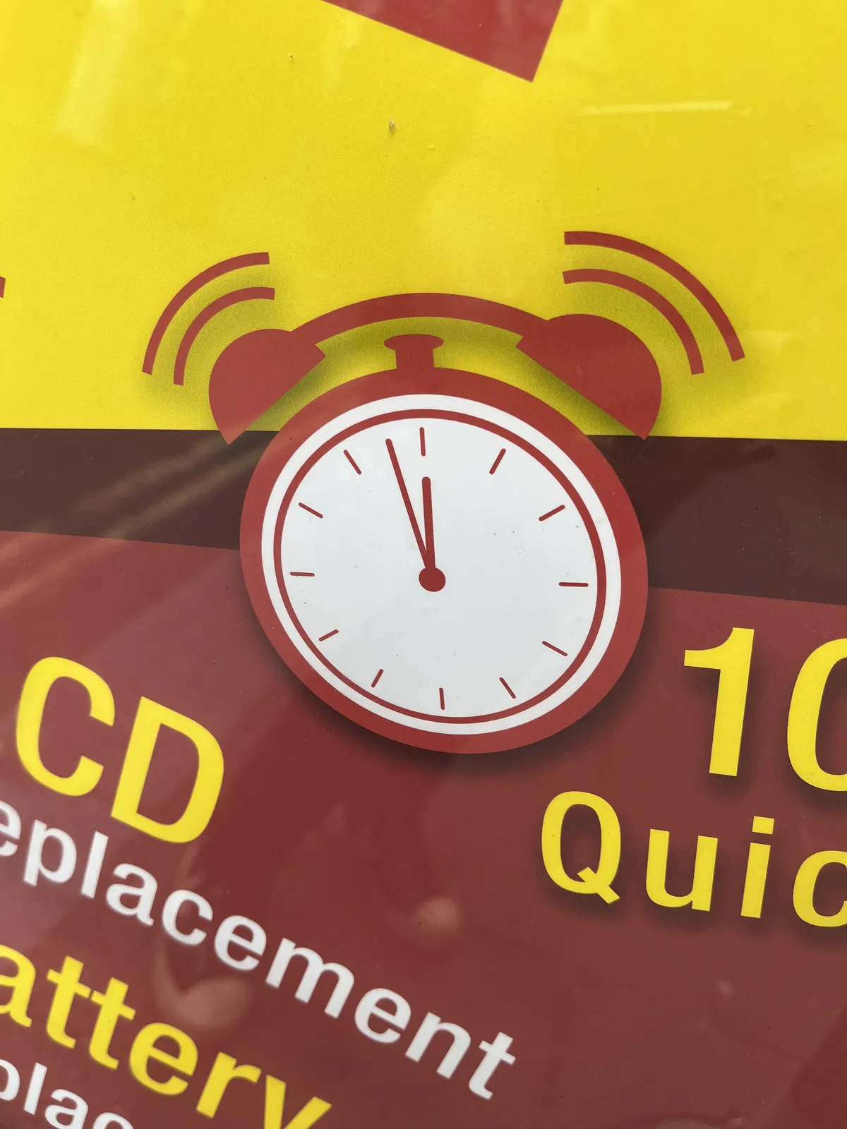 An icon of an old fashioned alarm clock on a yellow and red advertisement, that points at approximately two minutes to twelve.
