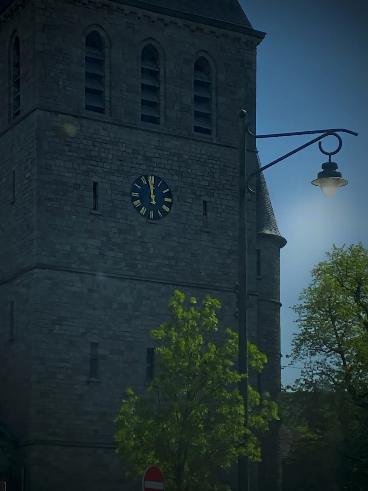 A heavy looking church with a clock. It points at 1 minute to 12.
