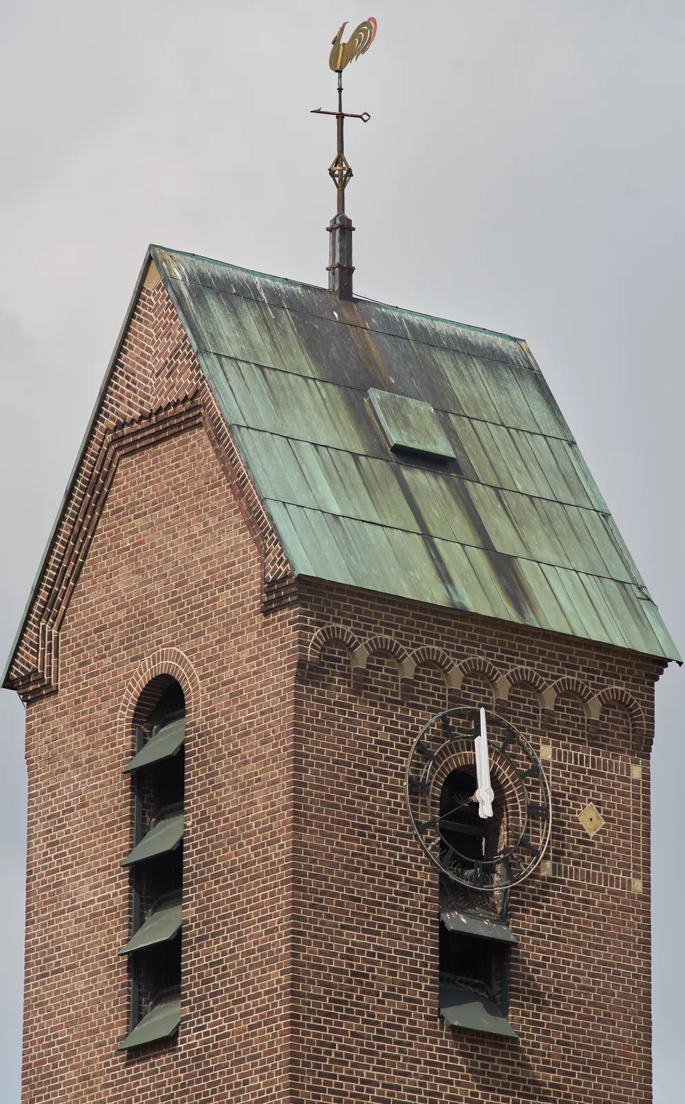 A church tower with a wind vane and a clock. It points at 1 minute to 12. 