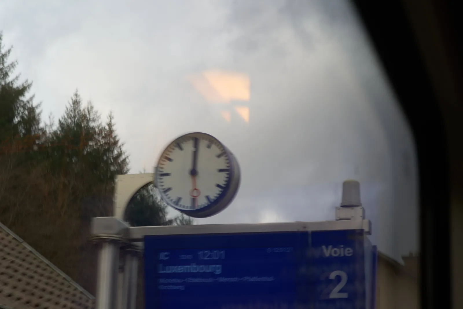 On track number two (voie deux in French), the train to Luxembourg is departing. This picture is taken from that train and the picture is a bit unsharp from the movement. The station clock points at one minute past 12.