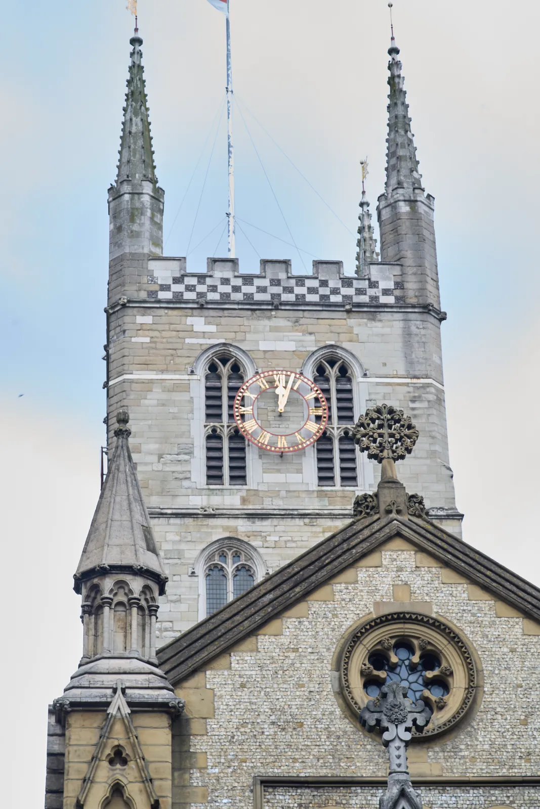 A large clock, attached to a large castle like chruch tower. The clock points at 3 minutes past twelve.