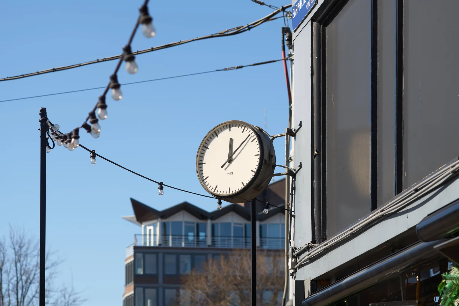 Attached to the facade of a bar there’s a clock that points at 8 minutes past 12.