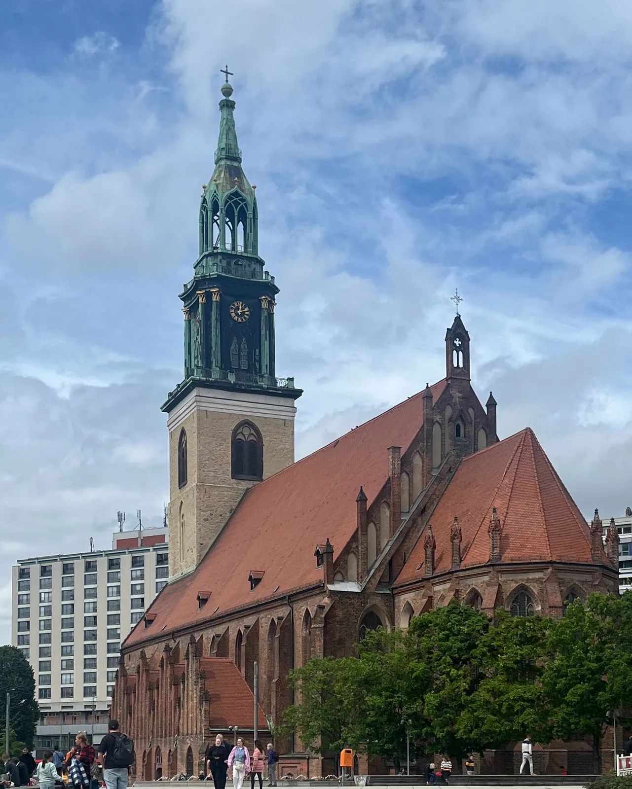 A church in a city. The clock on its tower points at 11 minutes past 12.