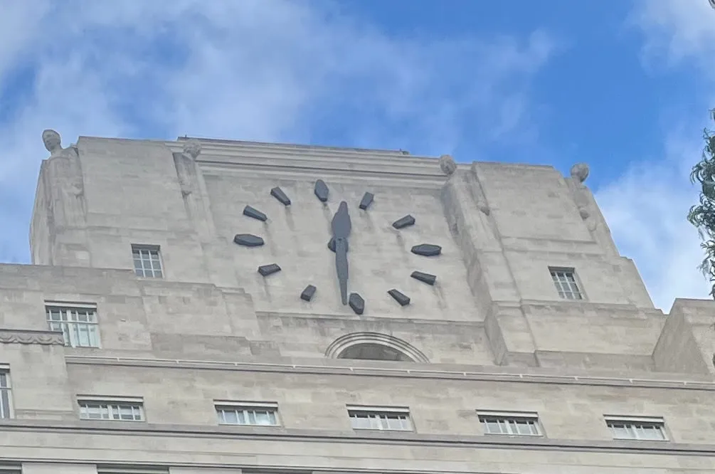 A huge clock built into the facade of an enormous, monumental building. It points at 29 minutes to one.