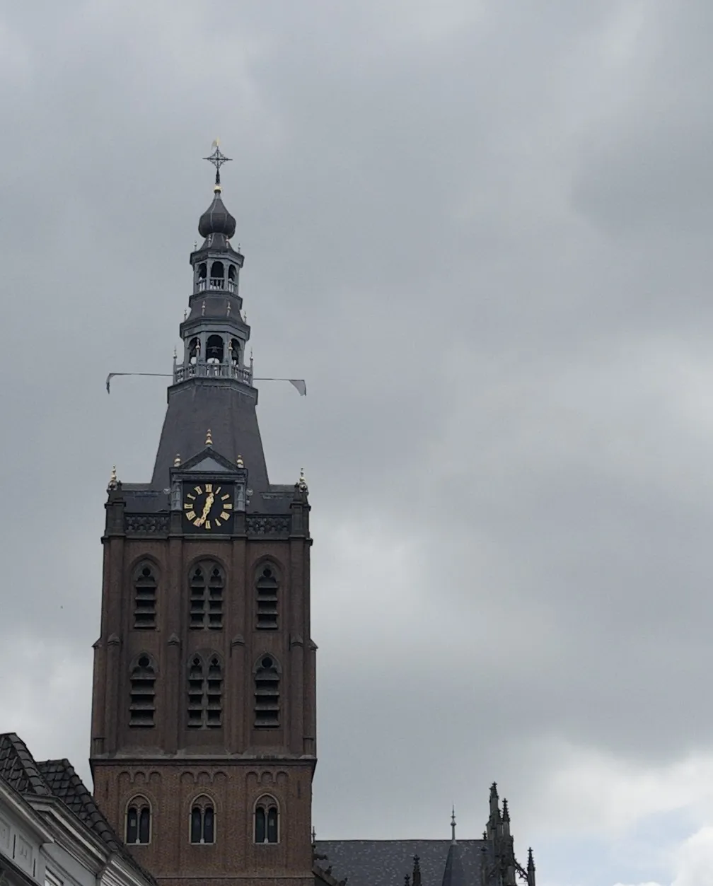A massive, old brick church tower with a clock on it that points at 33 minutes past twelve.