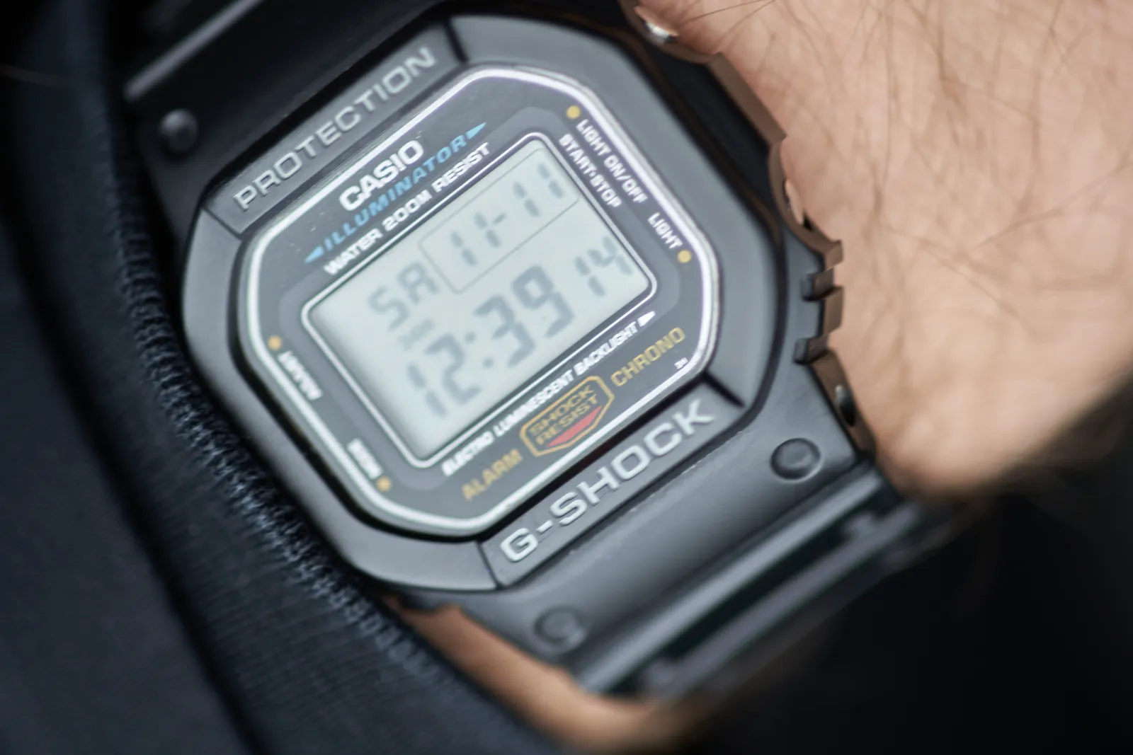 A Casio Protection, G-Shock, Illuminator watch on someone’s wrist. It shows the time, among other things, as 12:39.