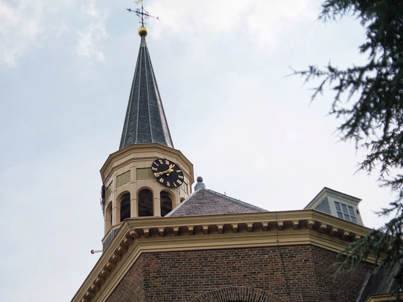 Looking up at a wooden church tower with a clock. It points at 20 minutes to one.