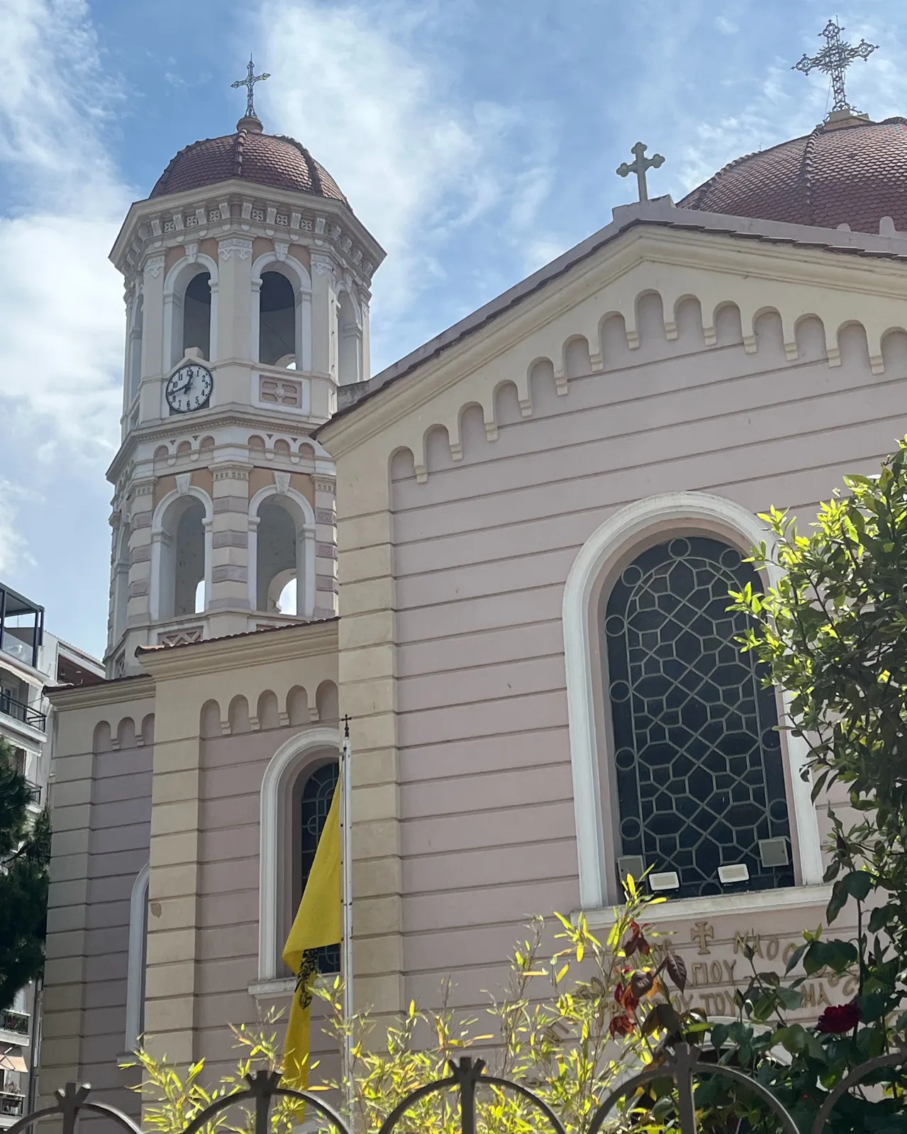A large, white, Greek church with a clock on its tower. It points at 16 minutes to one.