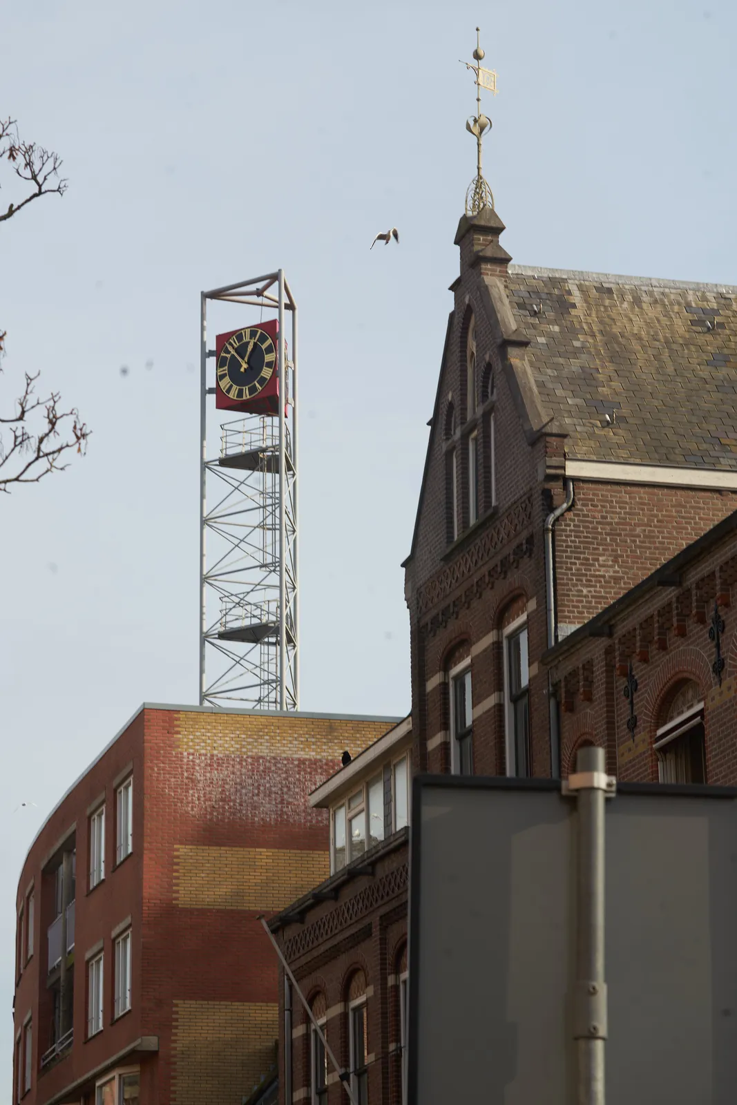 A clock on a high construction, towering over some Amsterdam homes, says it is 12:53