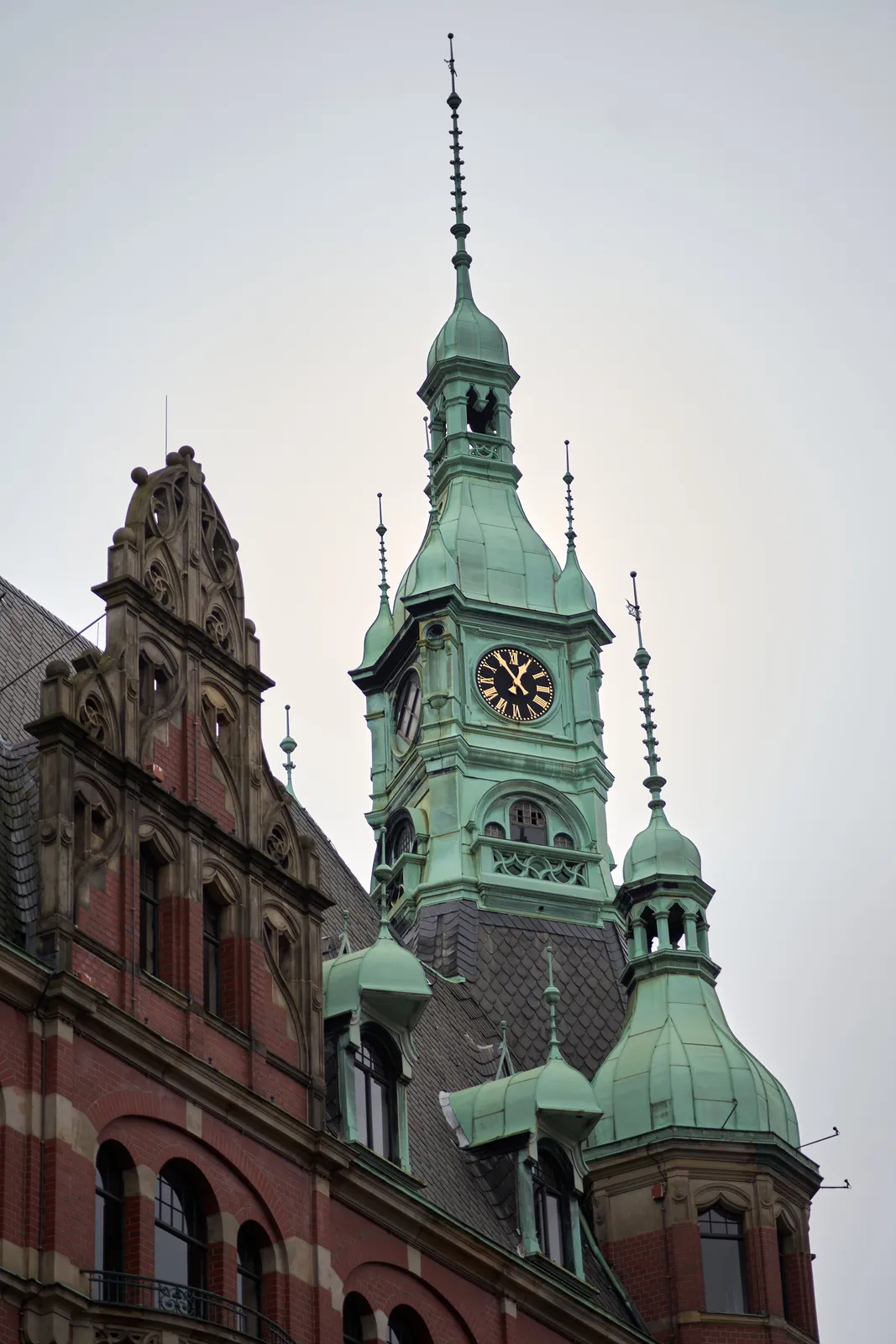 A brass dome and a brass towers on a frivolously ornamented building. There’s a clock on the tower which points at 5 to one.