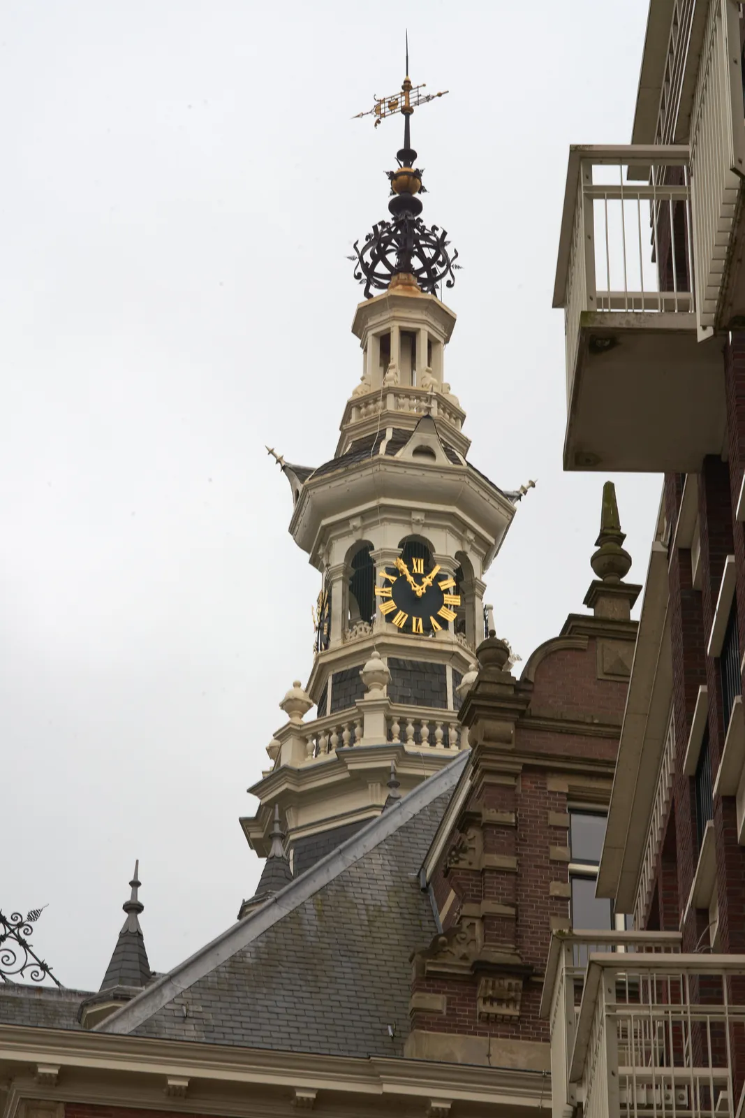 The golden hands of a clock on a church tower point at five to one. 