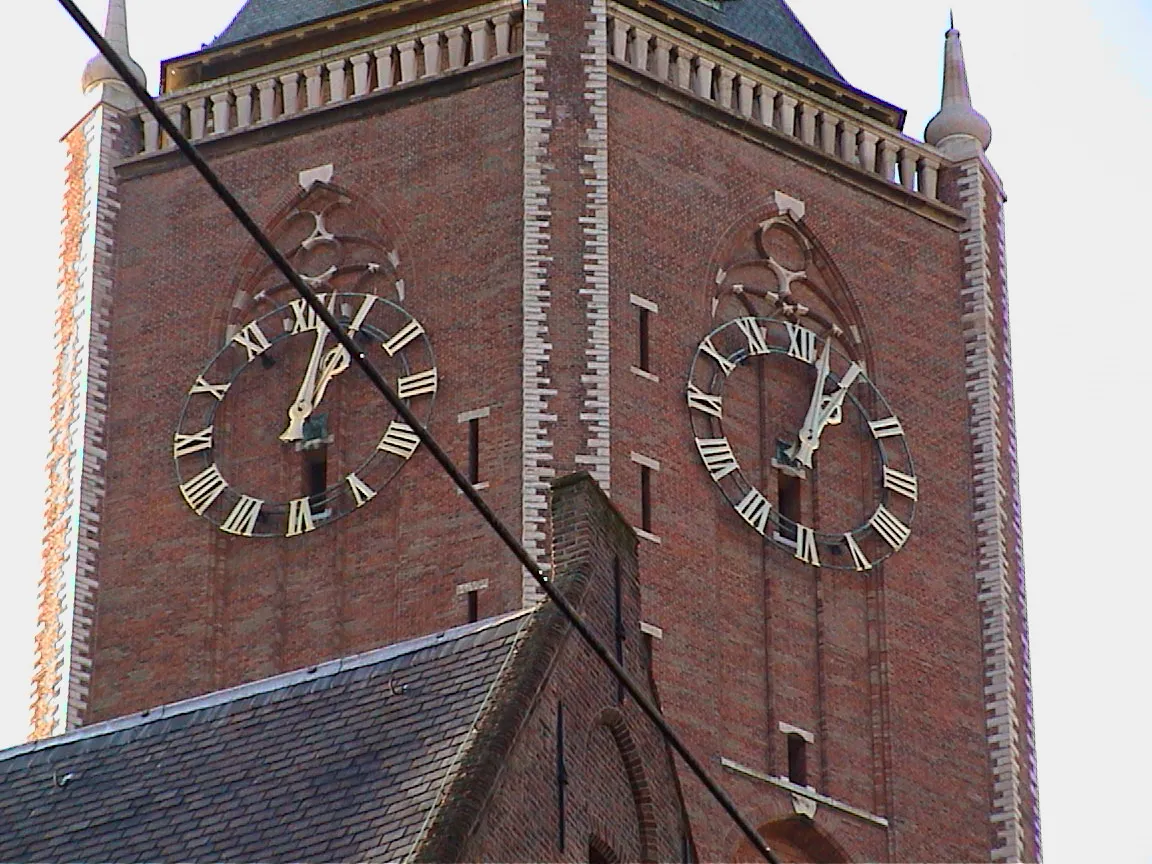 Two church clocks can be seen on the two visible sides of the church tower. All their hands point at 13:03.