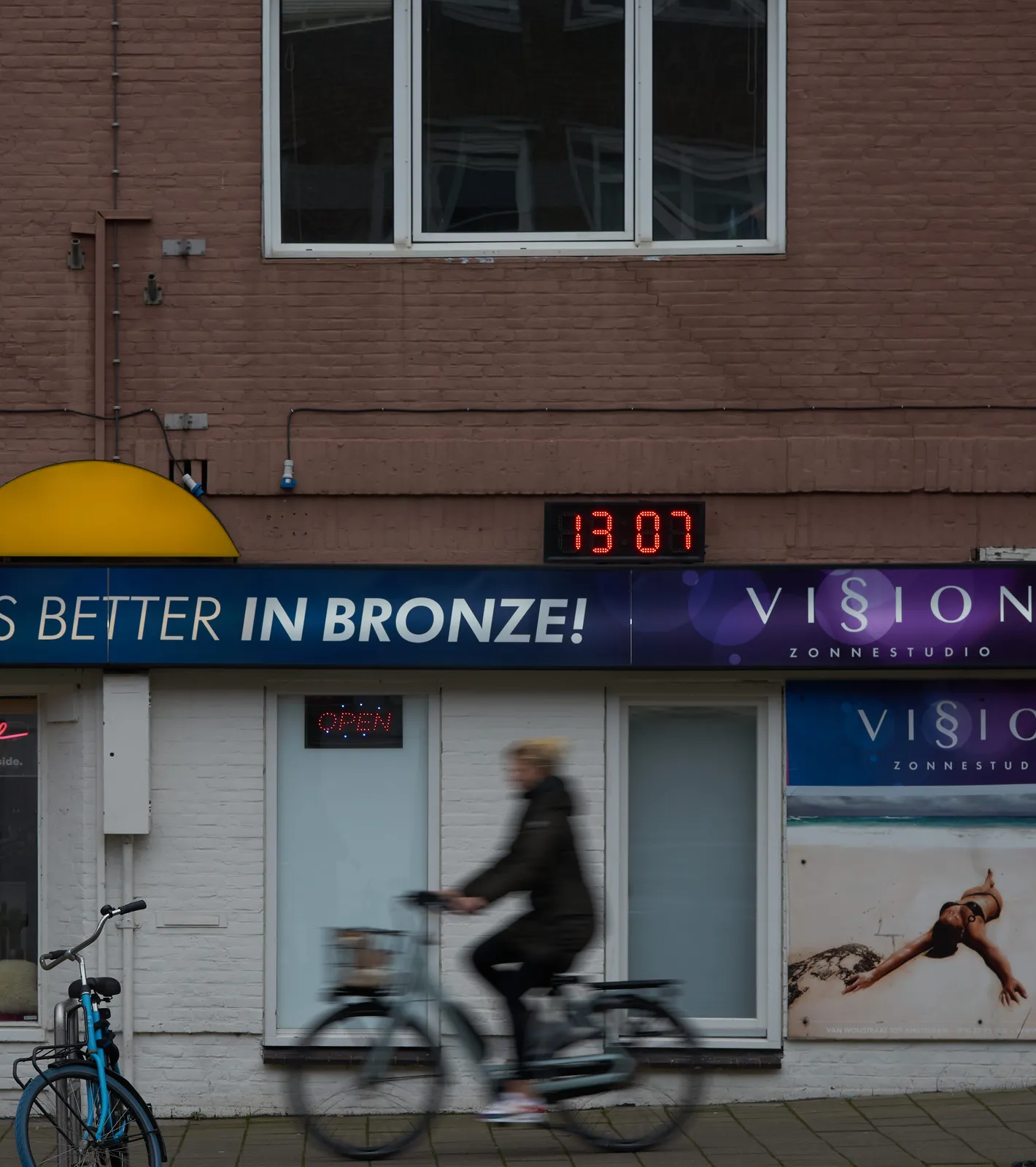 A clock on the facade of a tanning salon says it is 13:07