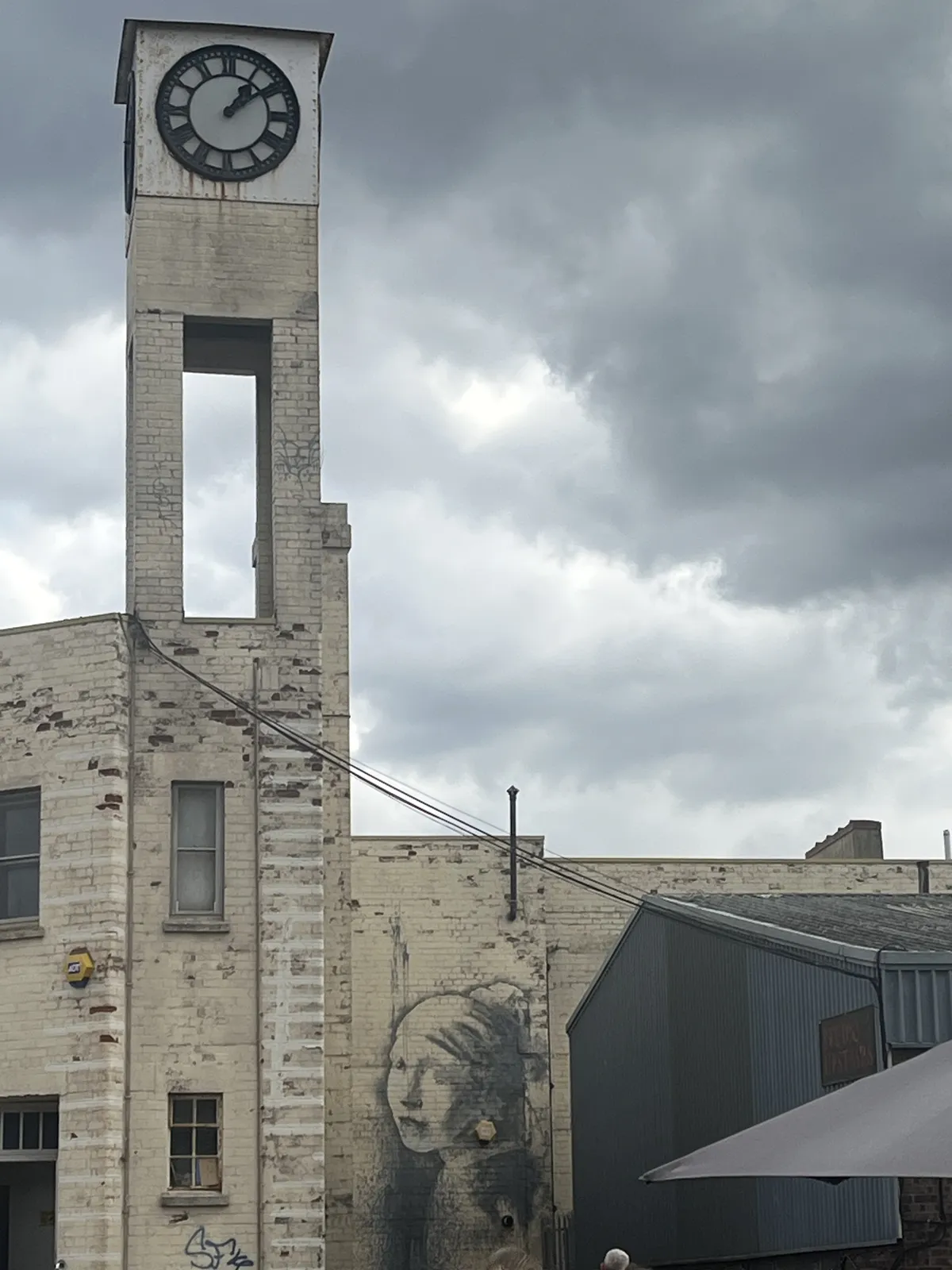 Next to a graffiti piece resembling the girl with a pearl earring, there’s a small tower with a clock on it which points at nine minutes past one.