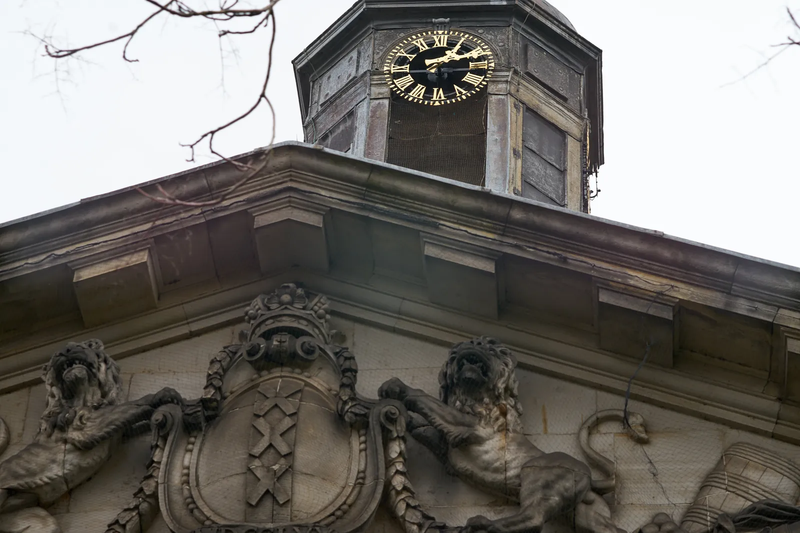 A golden clock on the Muiderpoort, an old city gate into the city of Amsterdam, points it 12 past one.